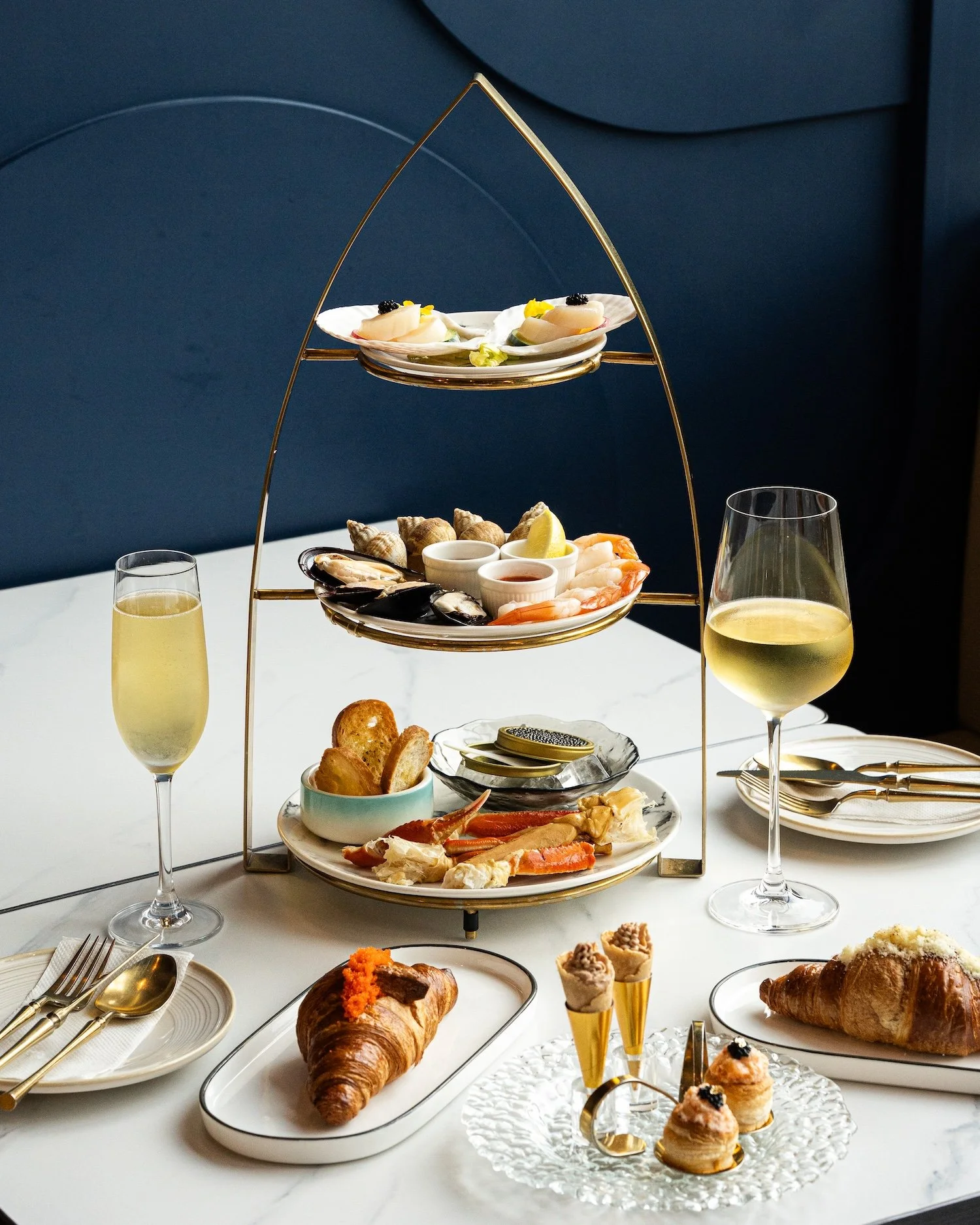 Plateau de fruits de mer avec crabes, crevettes, huîtres, mollusques, accompagnés de citron et sauces, avec une coupe de champagne sur une table élégante.