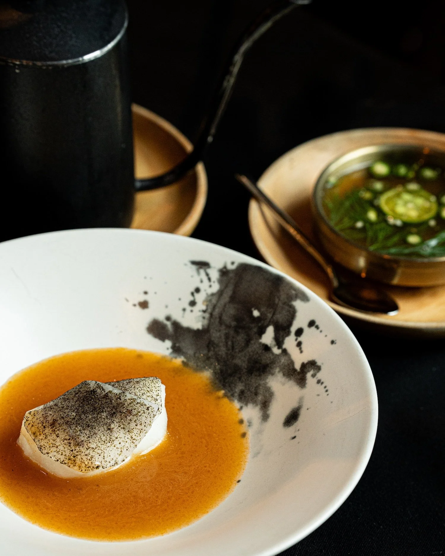 Soupe orange servie dans un bol blanc, garnie d'une tranche de champignon noir et d'une fine couche de poivre.