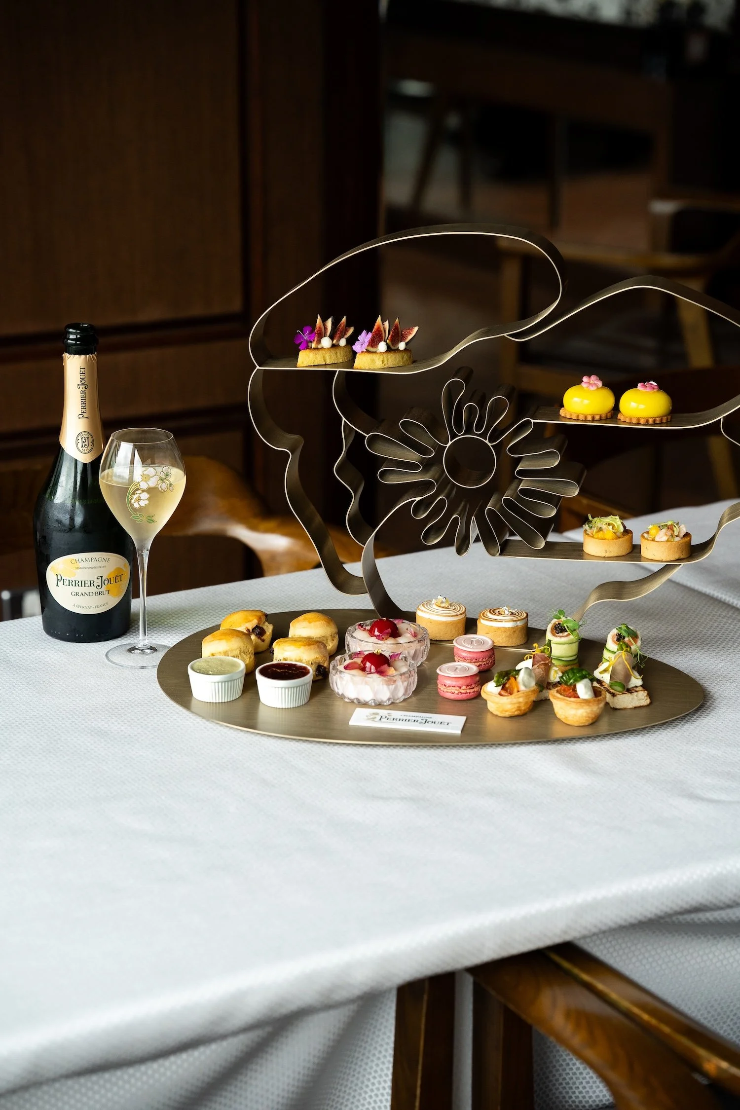 Un plateau de desserts élégants, un verre de champagne et une bouteille de champagne sur une table de restaurant.