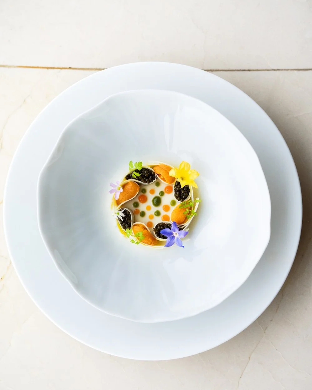 Assiette de présentation culinaire avec garnitures colorées et fleurs comestibles.