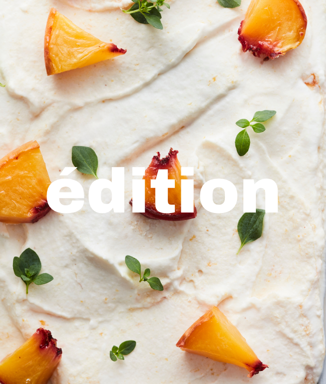 Dessert à la crème avec des morceaux de pêches et des feuilles vertes décoratives.