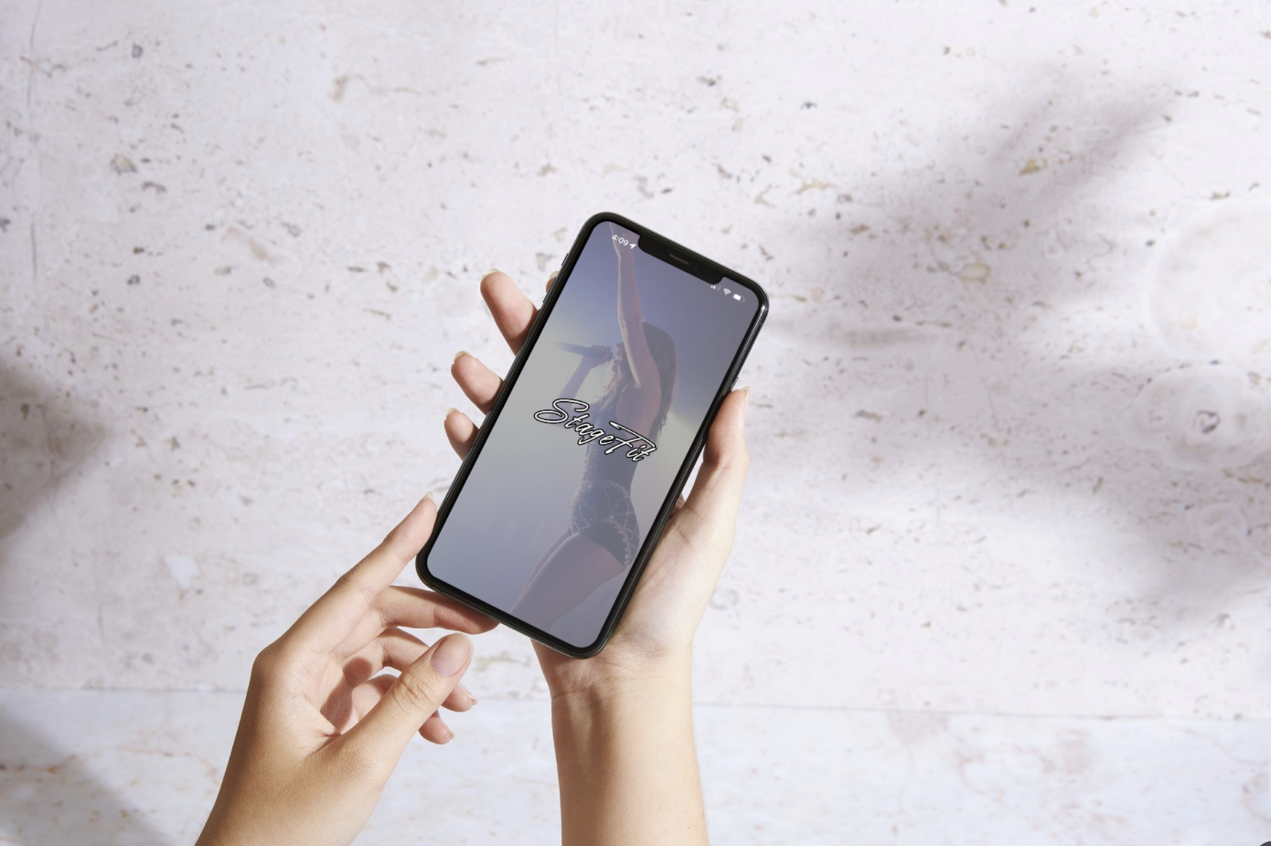 A person holding a smartphone displaying a fitness app with an image of a woman stretching and the text 'StretchFit' on the screen.
