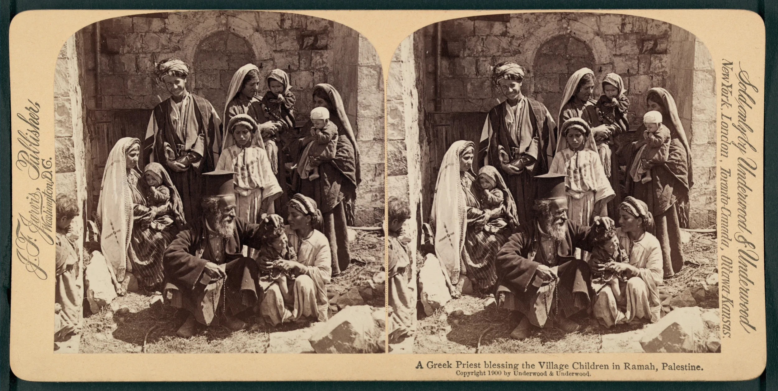 Black and white photograph depicting a Greek priest blessing children in the village of Ramah, Palestine. The scene includes several women and children standing and sitting in front of a stone wall, with the priest in traditional attire in the center