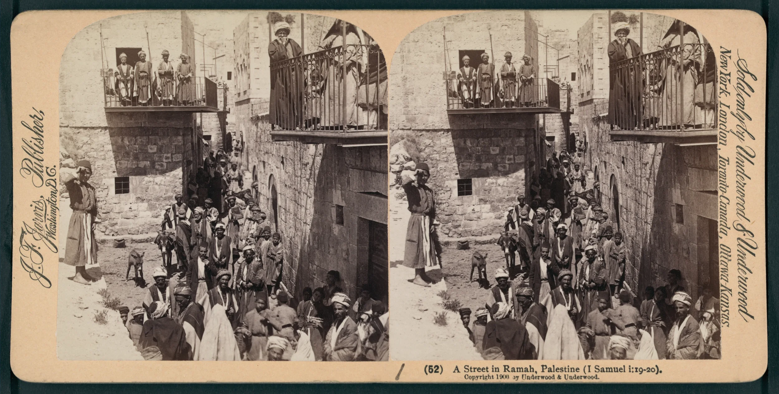 Historical black and white photograph of a street scene in Ramah, Palestine, showing men, women, and children gathered outside stone buildings with a balcony and iron railing. Some people are standing on the street, others on the balcony, with a few 