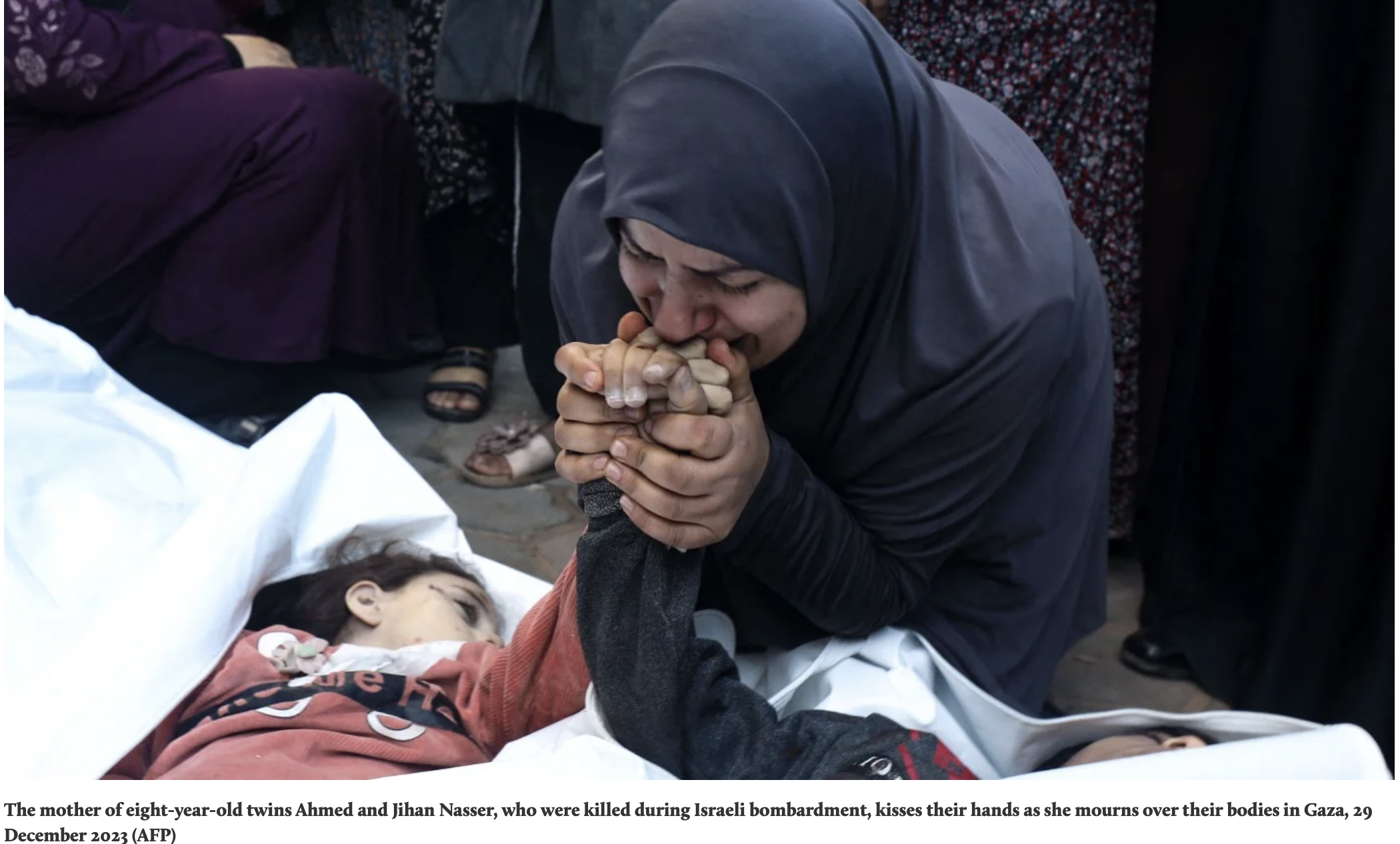 A woman wearing a black headscarf kisses the hands of a young girl lying in a bed. The setting appears to be a somber environment, likely mourning. The woman is sorrowful, with her eyes closed and an expression of grief.