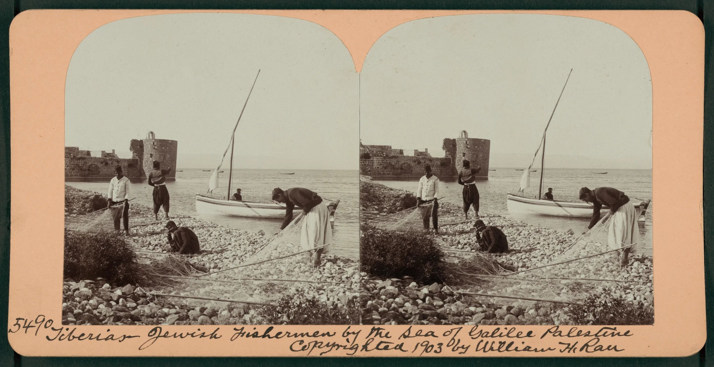A vintage black and white stereograph photo showing four Jewish fishermen on a rocky beach near a boat, with a castle in the background. The photo is labeled as taken in Gibraltar by the Sea of Galilee in 1903.
