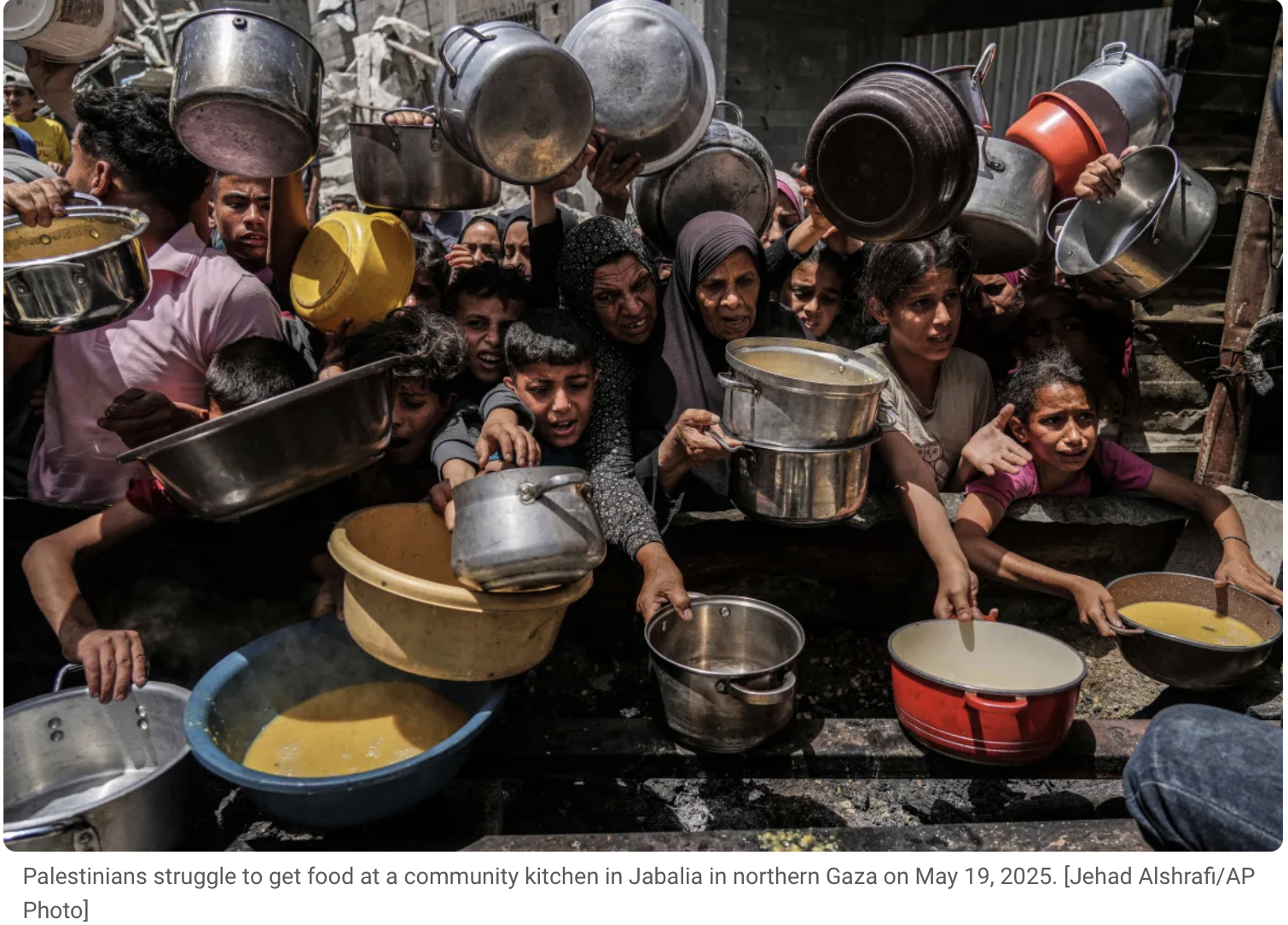 Palestinians crowd around a community kitchen with pots and bowls of food in Jabalia, northern Gaza, on May 19, 2025.