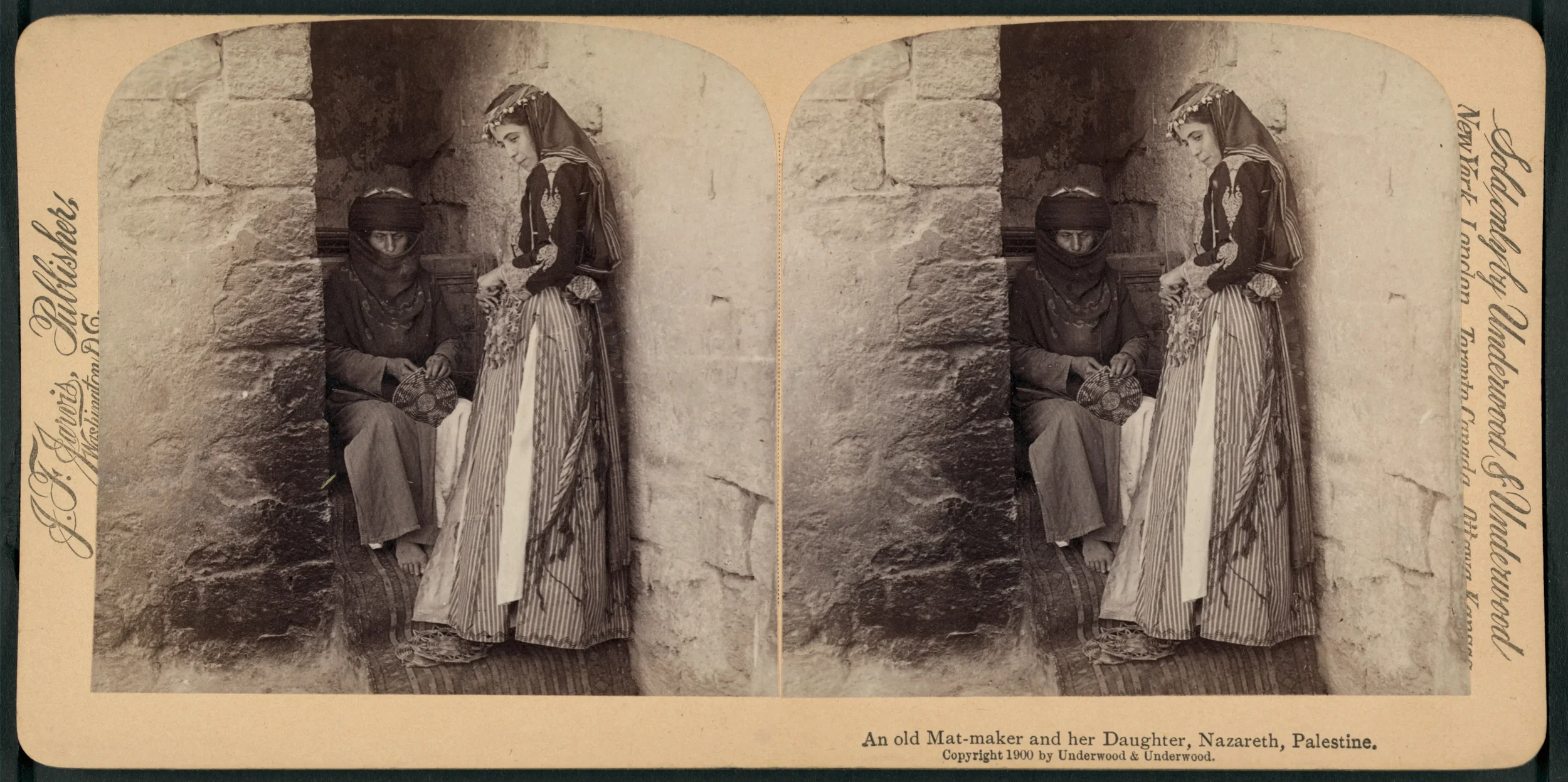 A vintage black and white photograph of a woman and a girl, possibly mother and daughter, standing and sitting against a stone wall in Nazareth, Palestine. The woman is seated with a basket, wearing traditional clothing and a head covering. The girl 