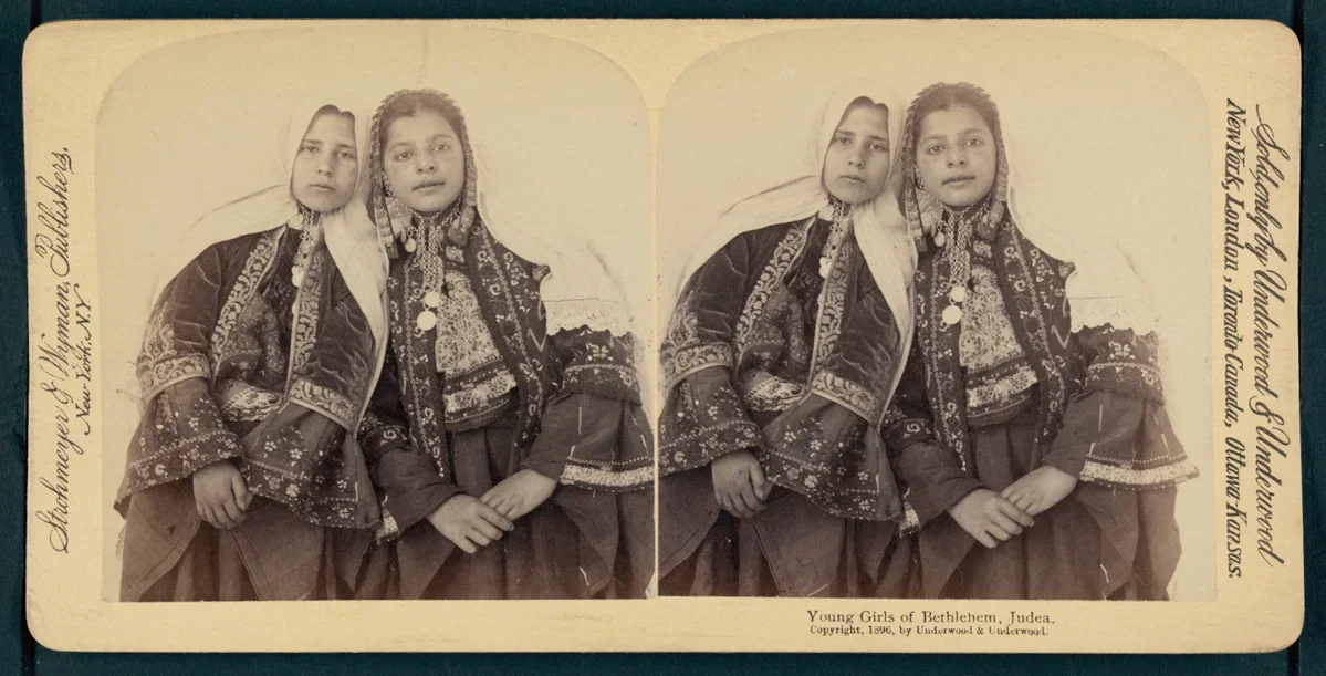 Black and white photograph of two young girls from Bethlehem, Judea, dressed in traditional folk clothing, standing side by side with serious expressions.