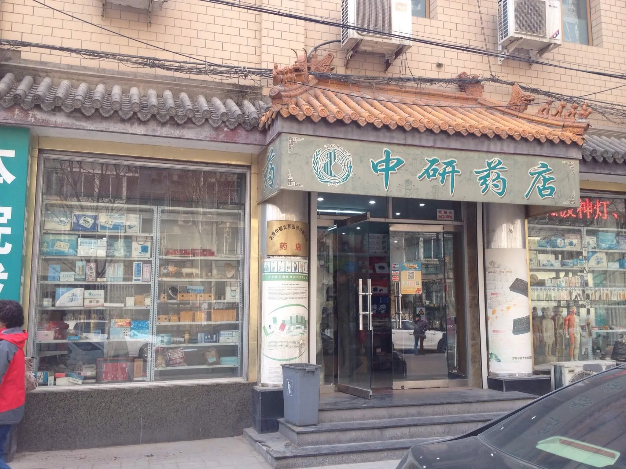 Exterior of a traditional Chinese medicine pharmacy with Chinese characters on the sign and decorative rooftop figures of mythological creatures.