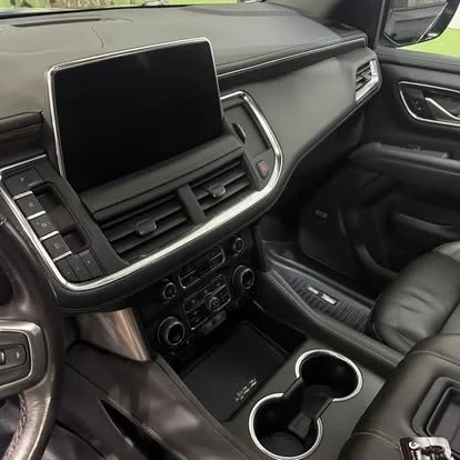The interior of a vehicle dashboard showing a large touchscreen display, air vents, climate controls, and cupholders in the center console.