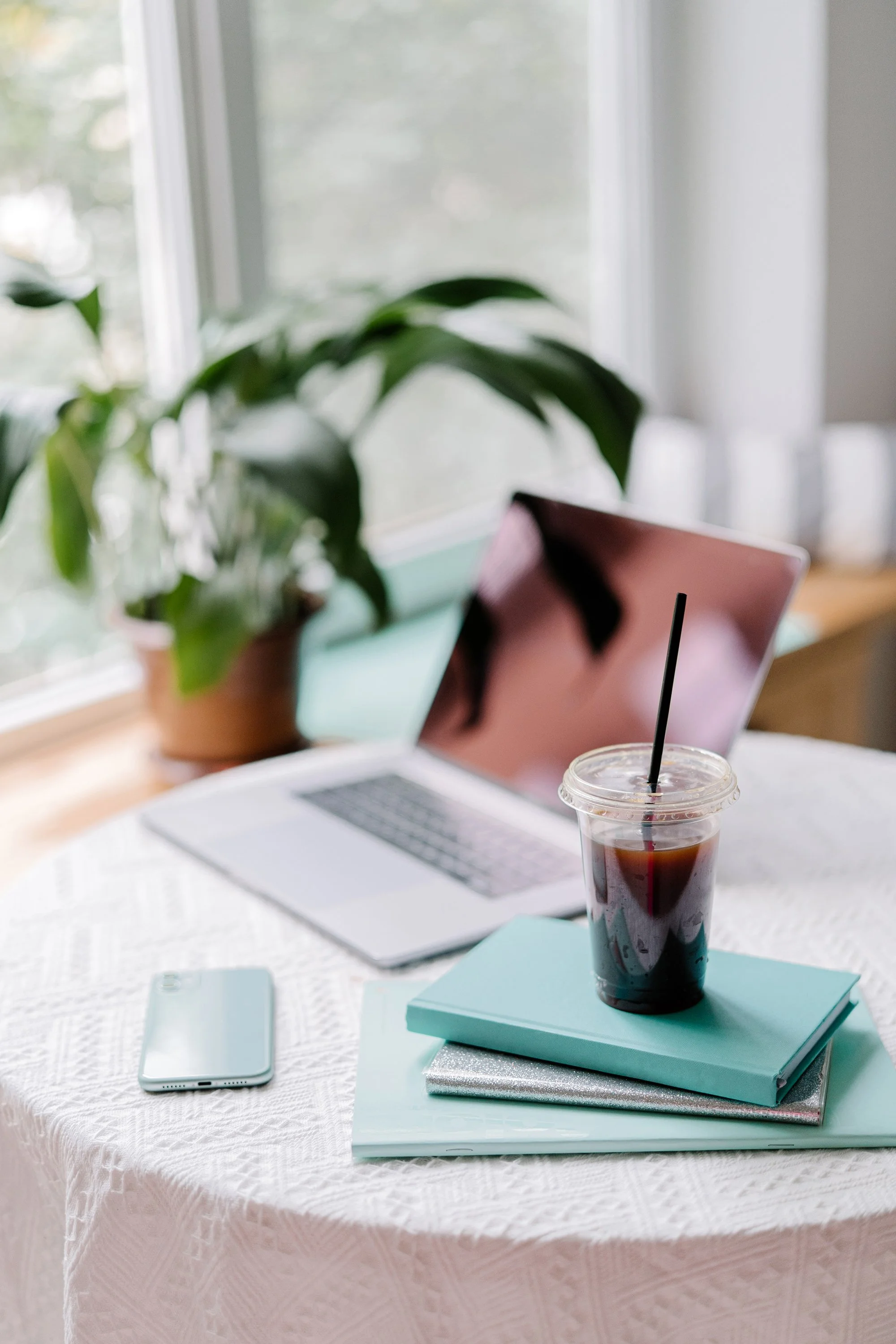 Photo of a desktop with a plant, laptop, and coffee