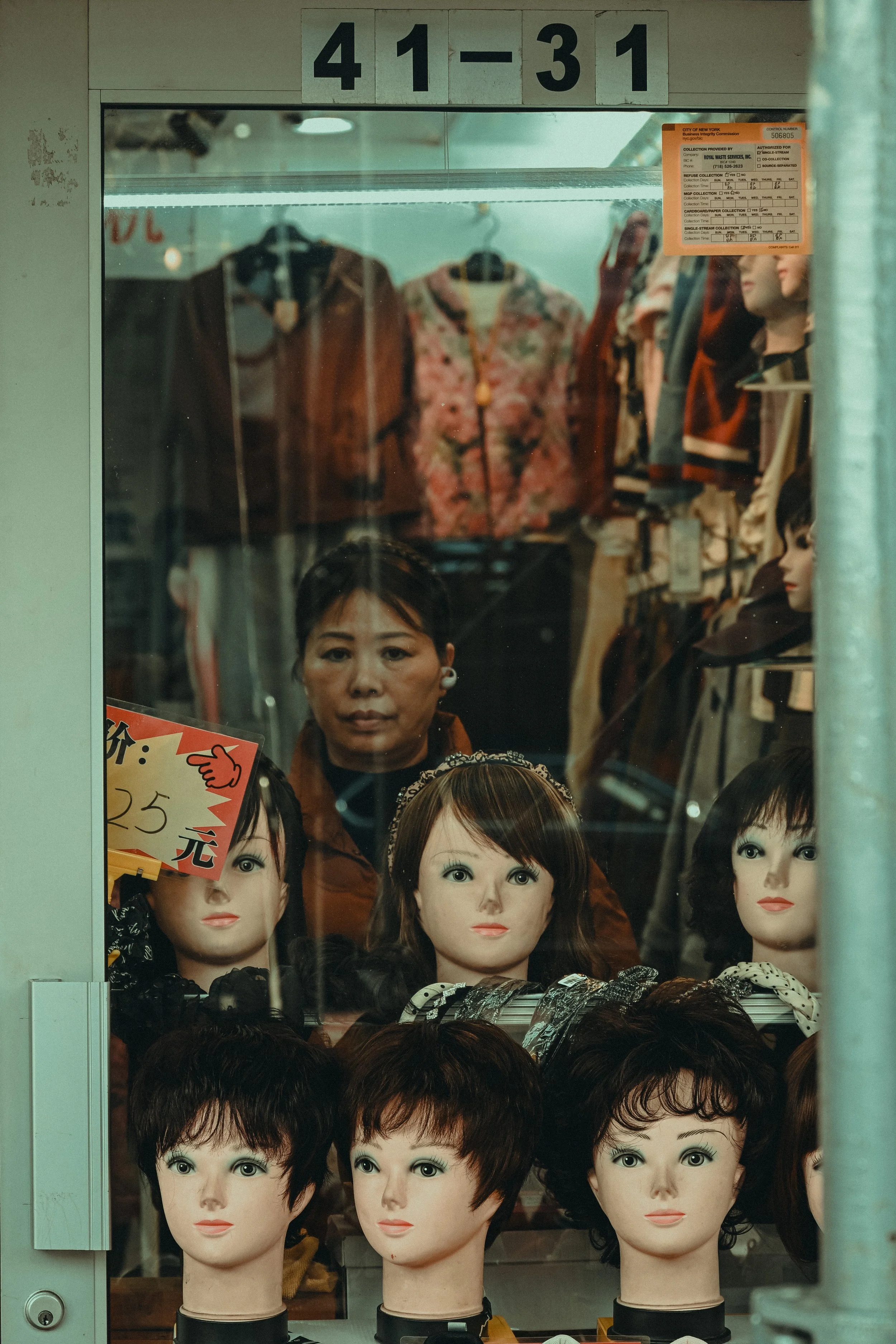 Variety of mannequin heads with different hairstyles on display inside a store window.