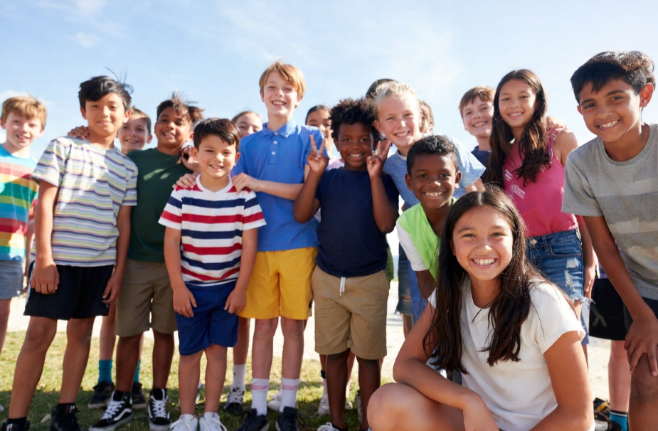 Group of diverse children smiling outdoors on a sunny day.