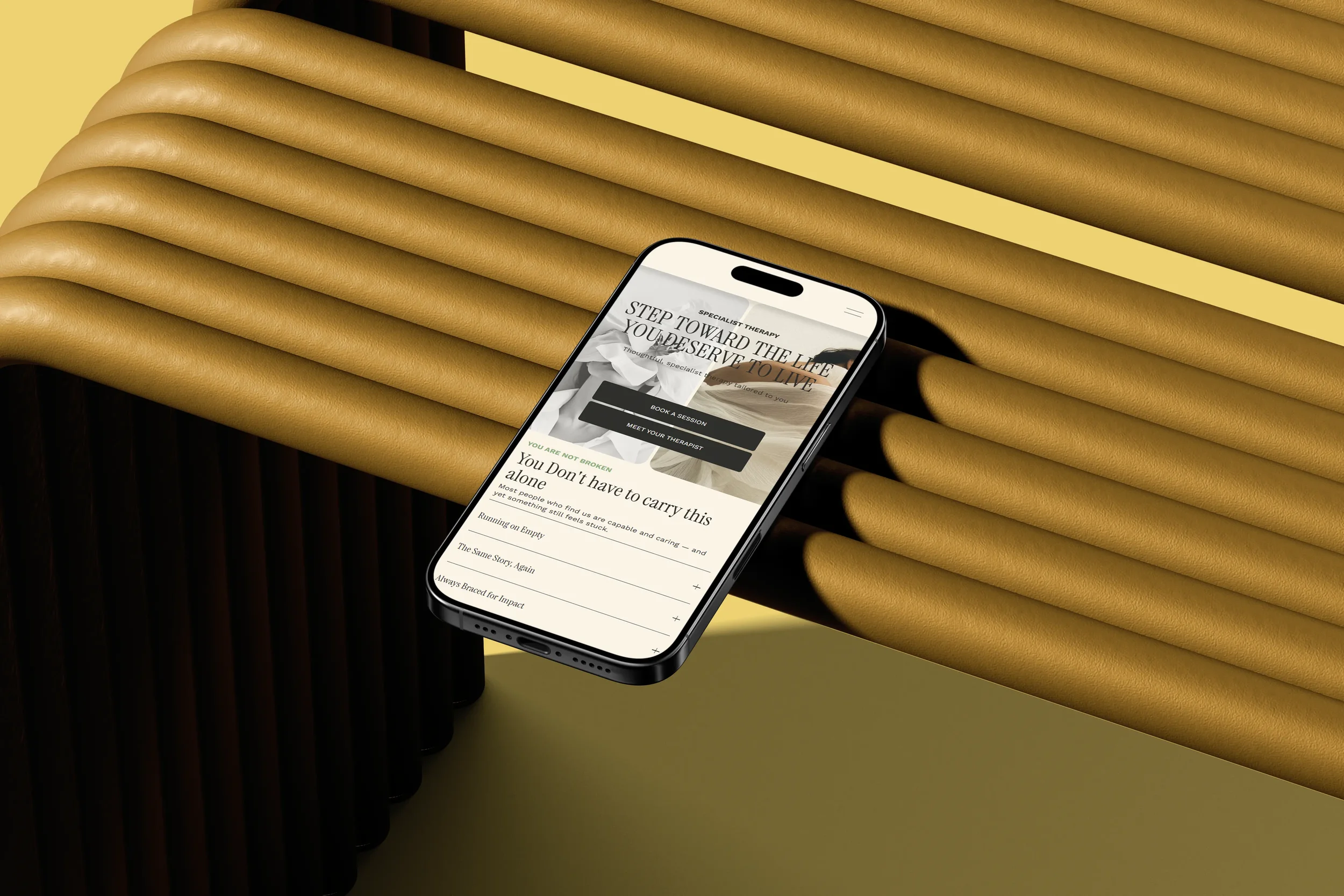 A smartphone displaying a webpage or app with the text "Step toward the life you deserve to live" on a yellow surface next to a wooden slatted bench.