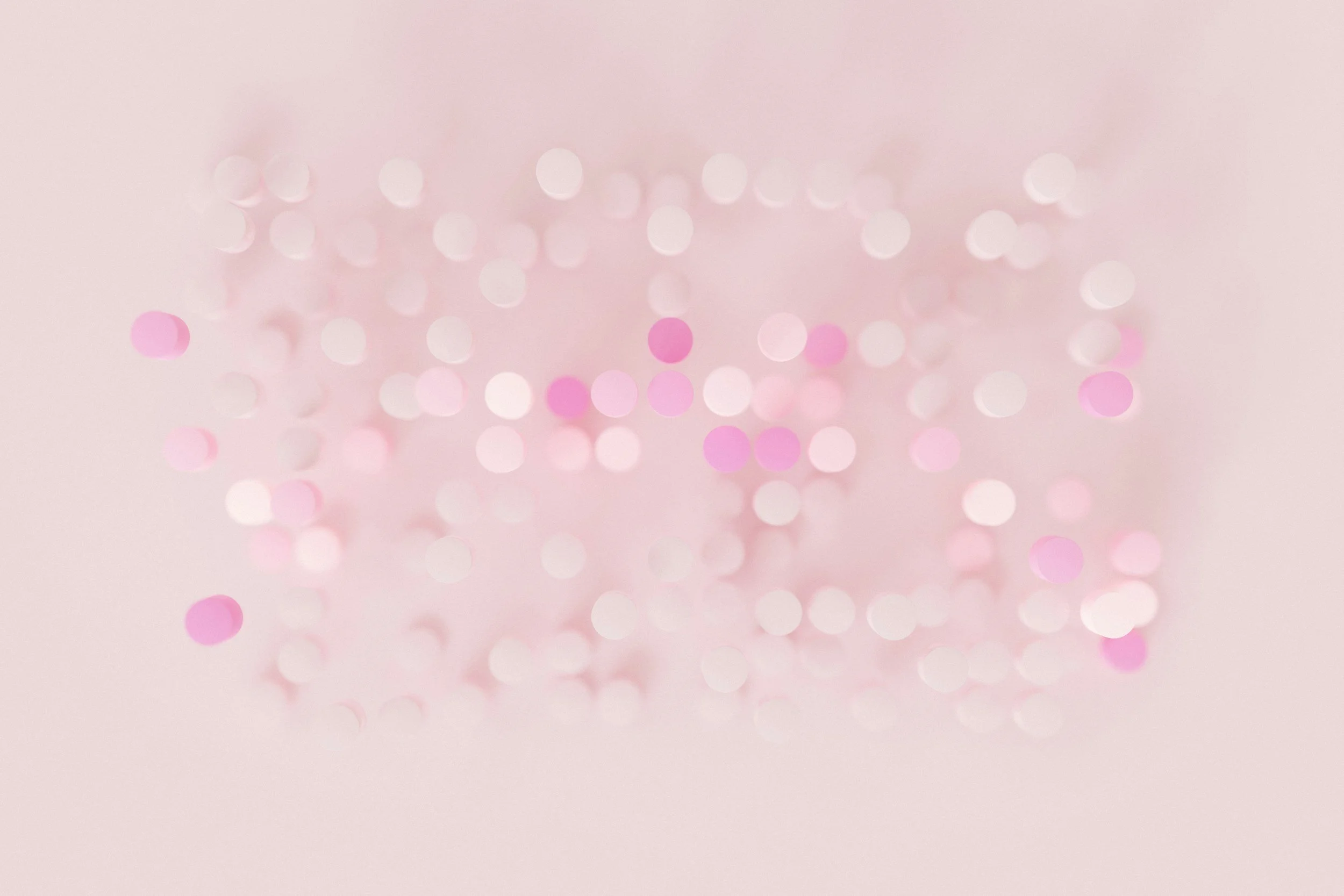 A soft pink background with scattered pink and white circular confetti.