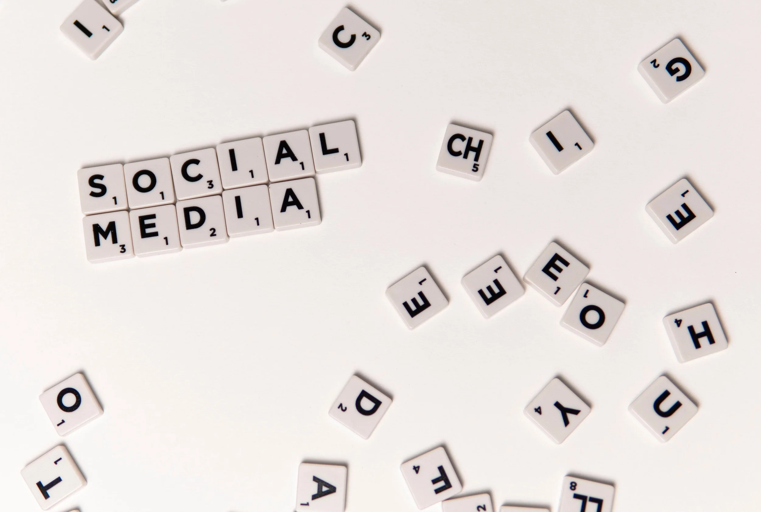 White tile letter blocks spell out 'SOCIAL MEDIA' on a white background, with scattered letter tiles around.