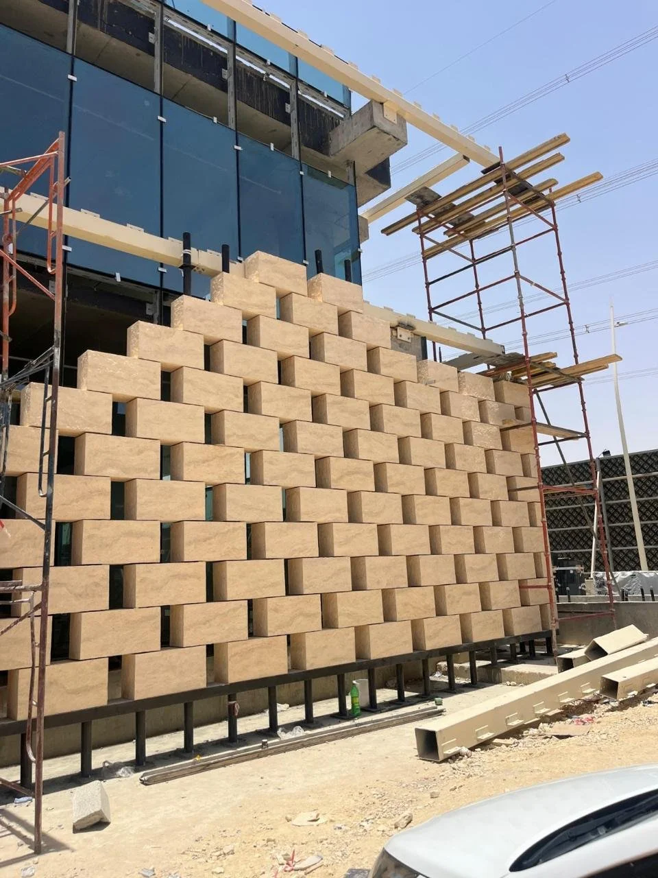 Under construction building with a brick facade, scaffolding on the sides, and blue-tinted glass windows.
