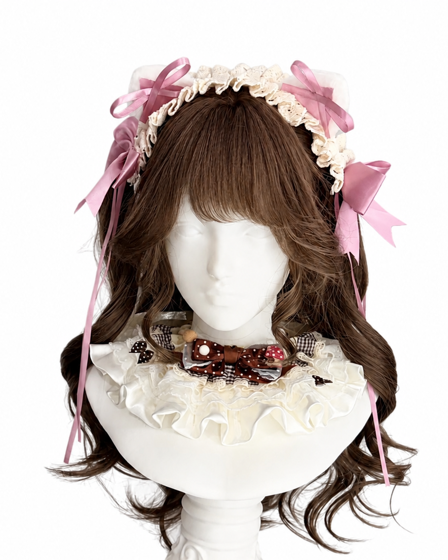 Mannequin wearing long, wavy brown wig with bangs, decorated with a ruffled lace headband and pink ribbons, also wearing a frilled collar with bows.