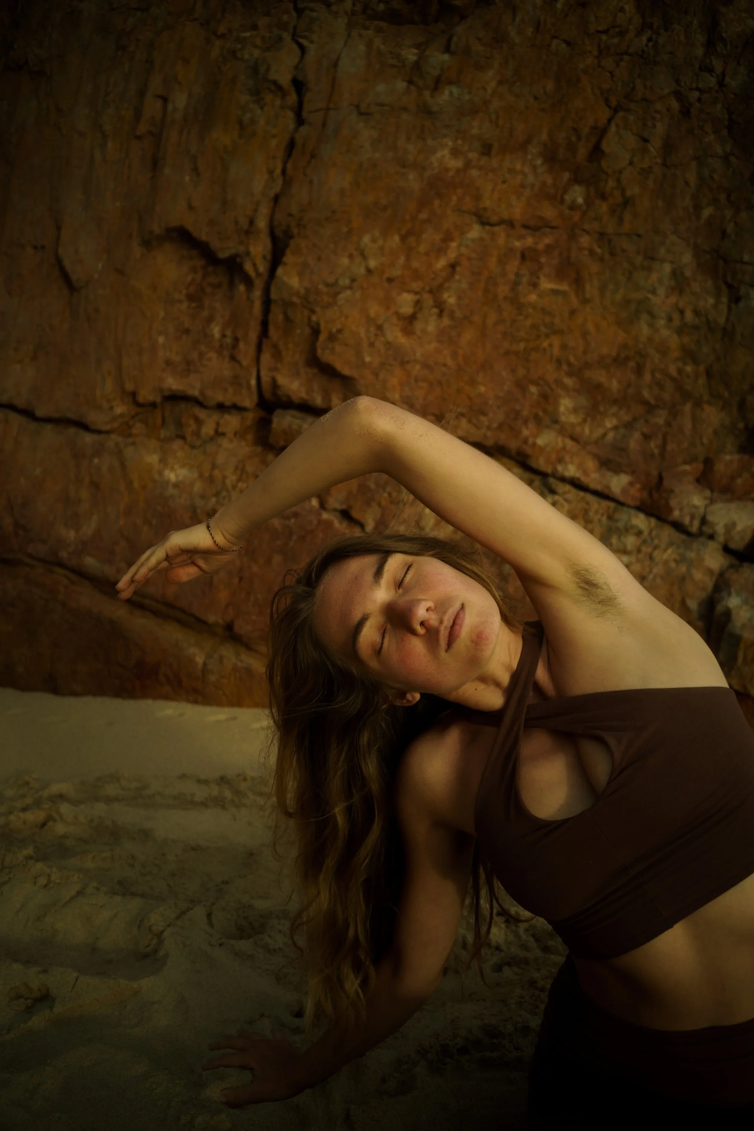 Frau macht Yoga vor einer Felswand in einer Höhle.