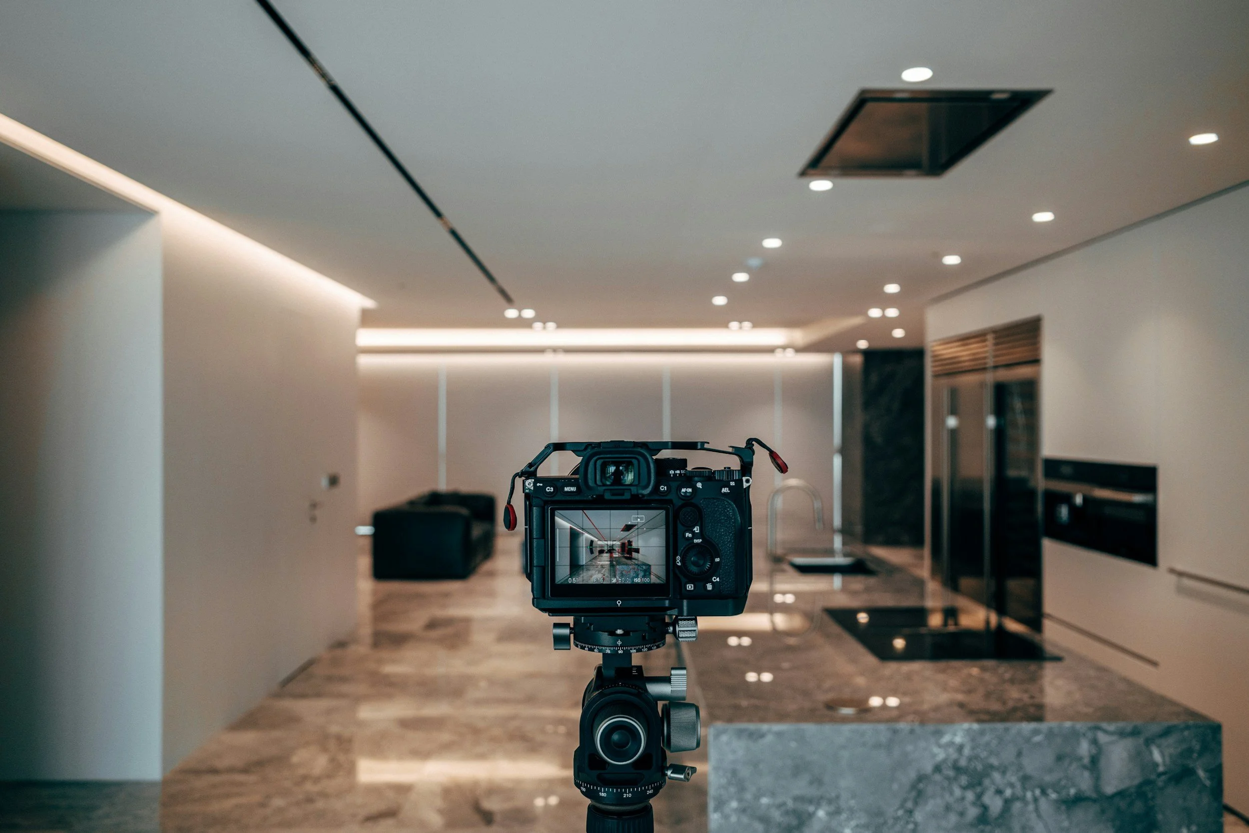 A professional camera on a tripod in a modern, well-lit indoor setting, possibly a reception or lobby area.