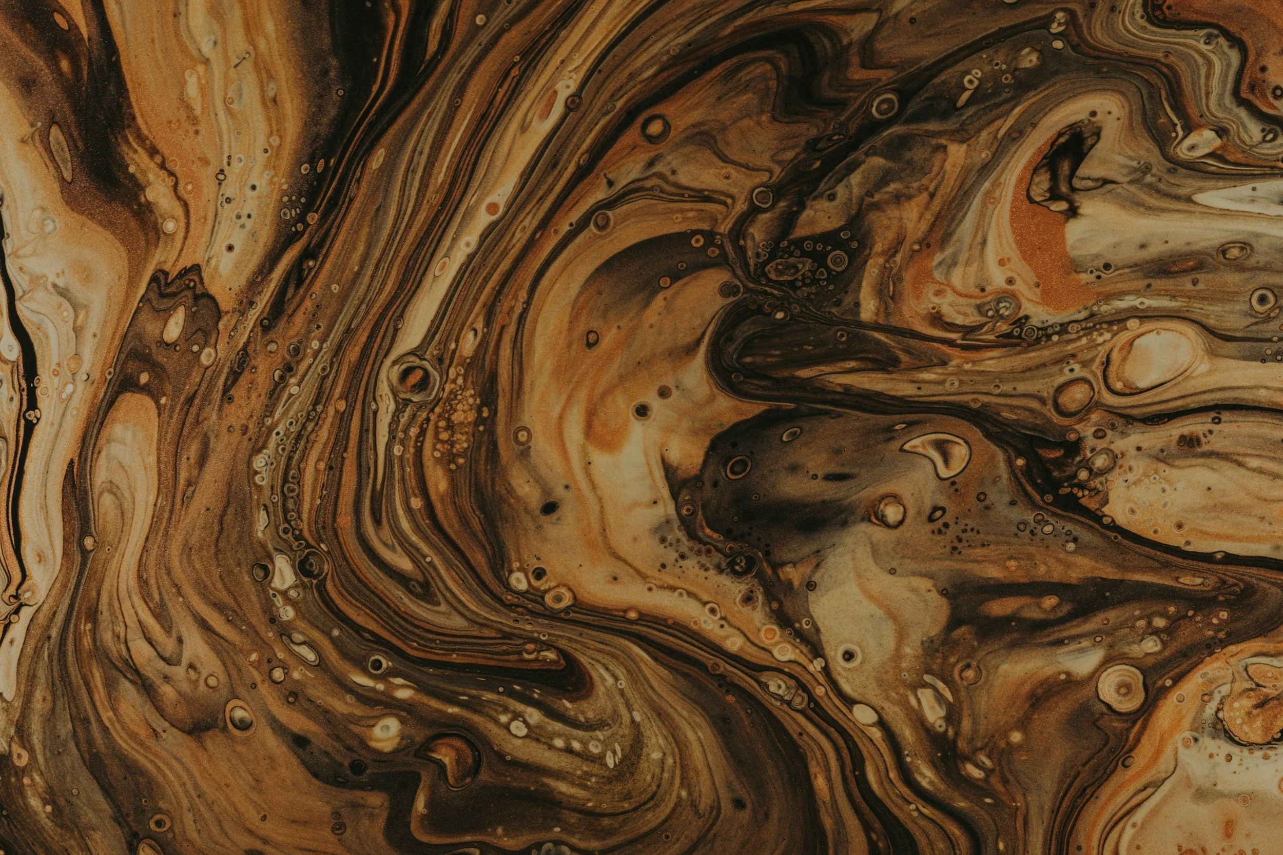 Swirling patterns of brown, black, tan, and cream resembling marbled liquid or abstract art.