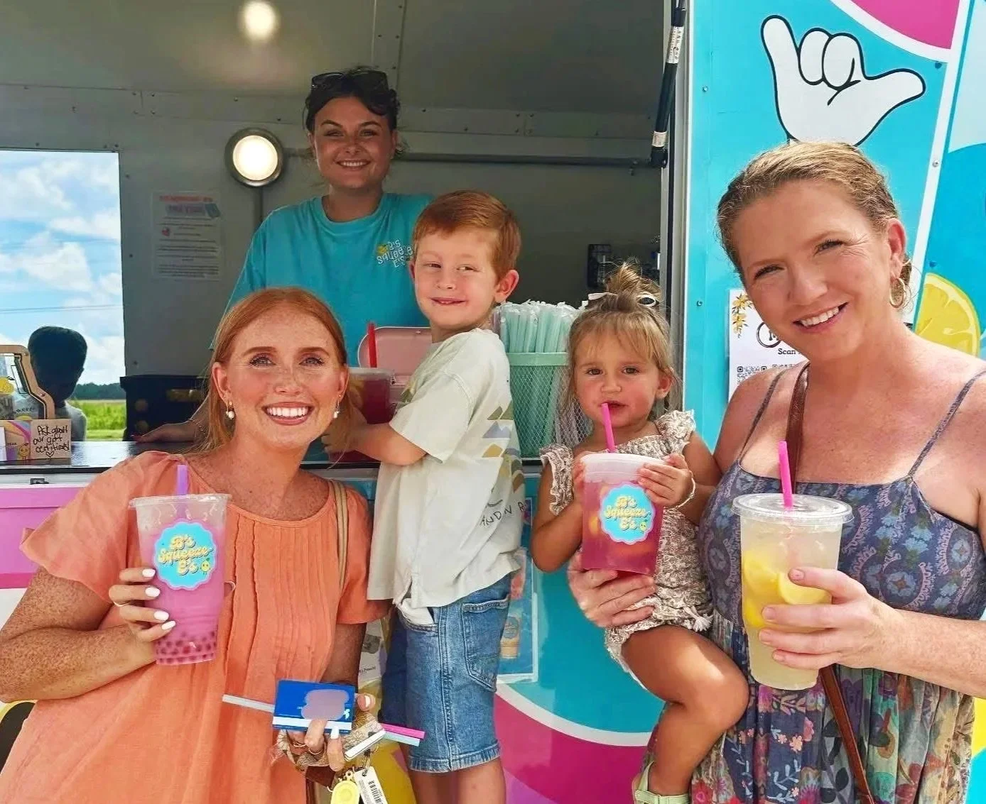 People enjoying icy drinks at an outdoor event with an ice cream truck in the background.