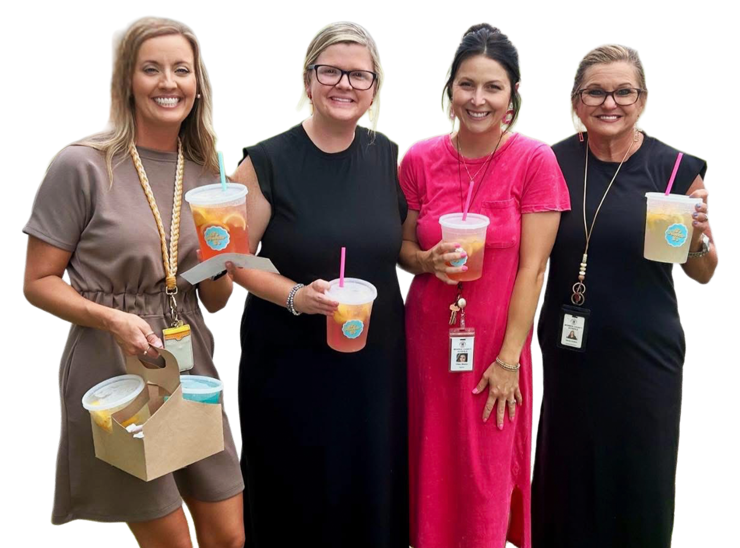 Four women standing together, smiling, holding cups of beverages with pink, blue, and yellow straws, wearing casual dresses and identification badges.