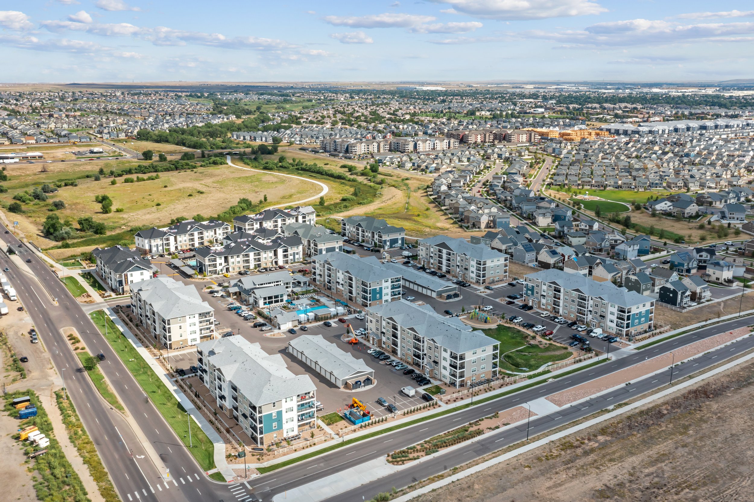 An aerial view of a suburban neighborhood with multiple residential buildings, roads, and green spaces.