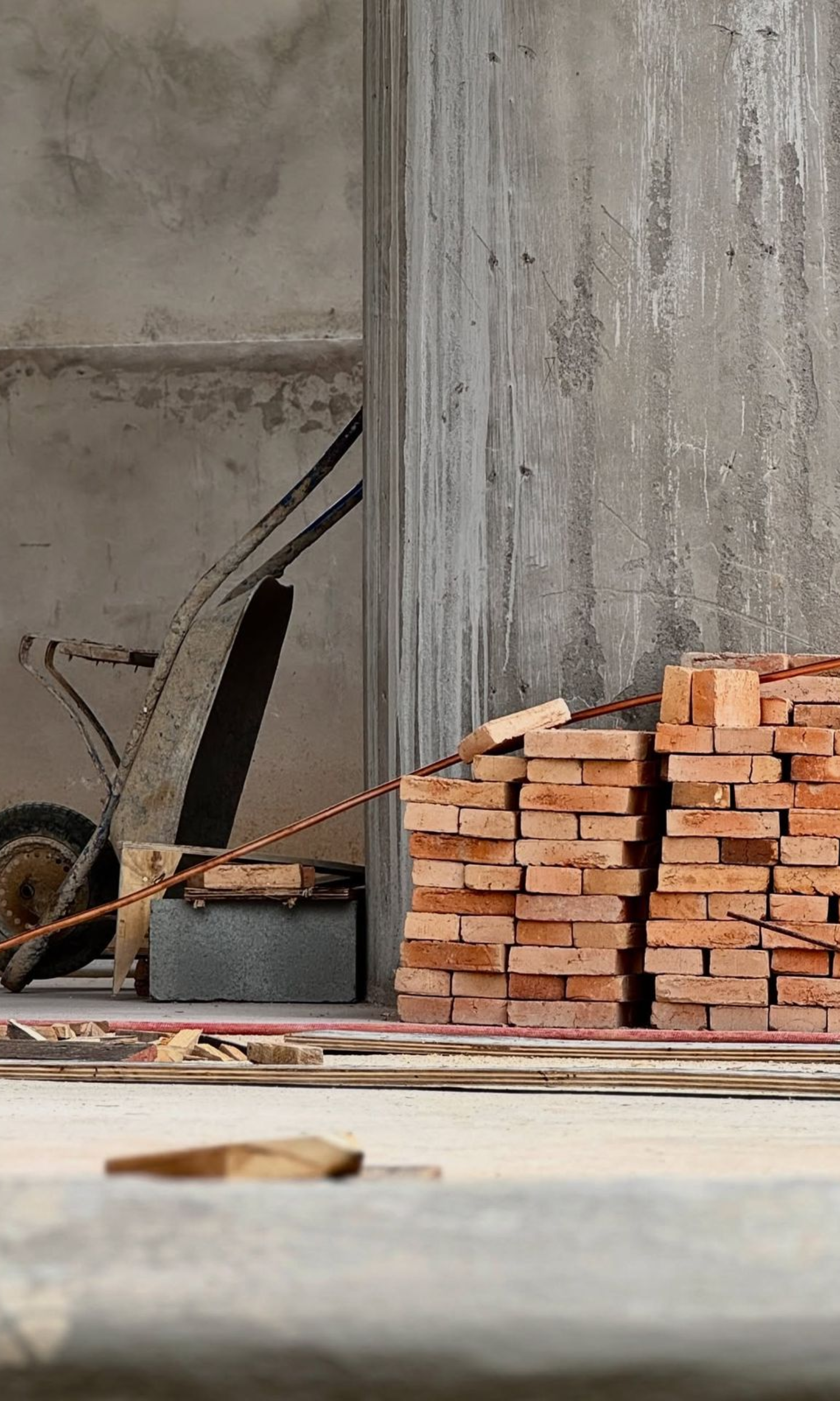 Construction site with a wheelbarrow, a stack of bricks, and building materials.