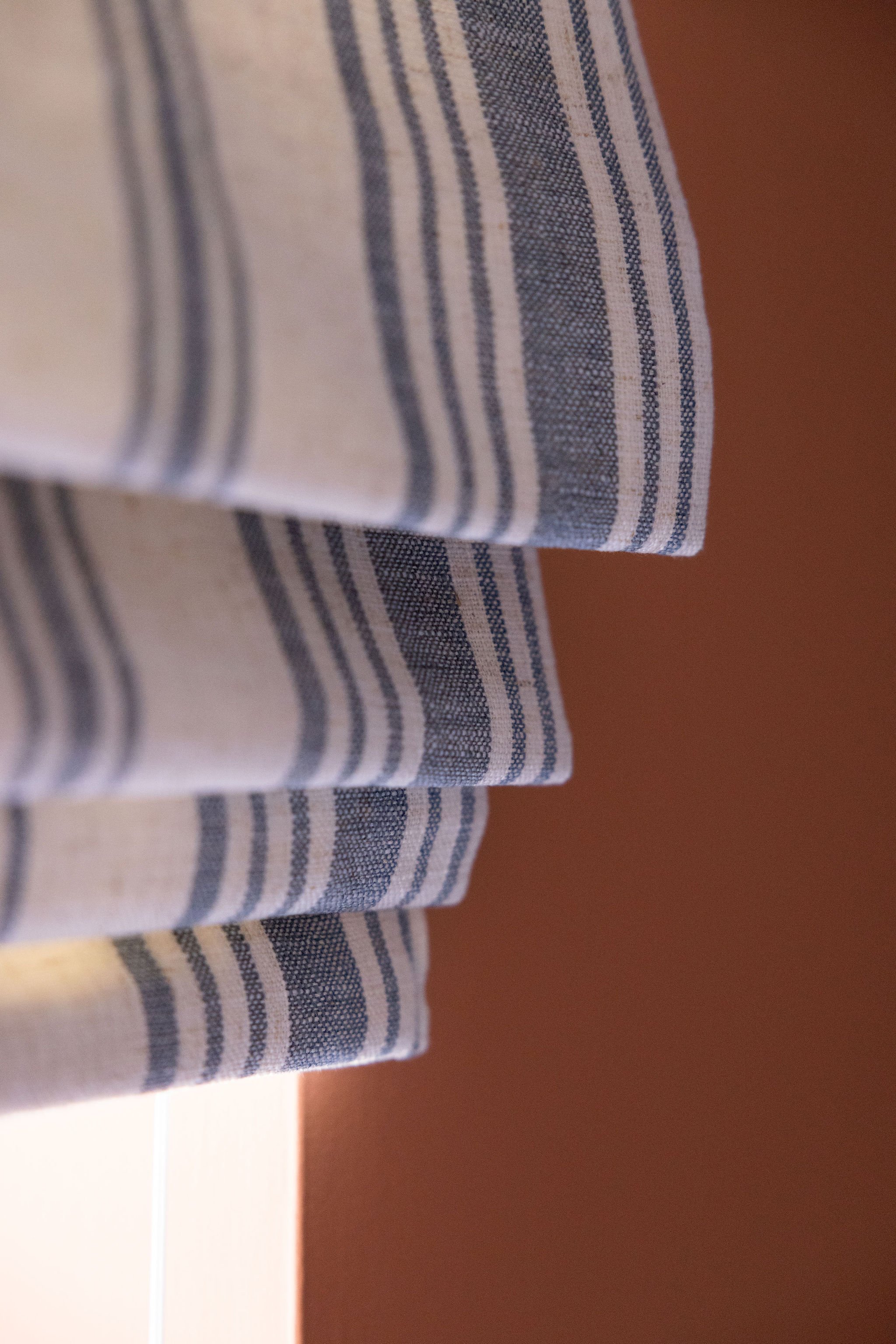 Close-up of a fabric with horizontal navy and white stripes, draped over an orange-brown surface.