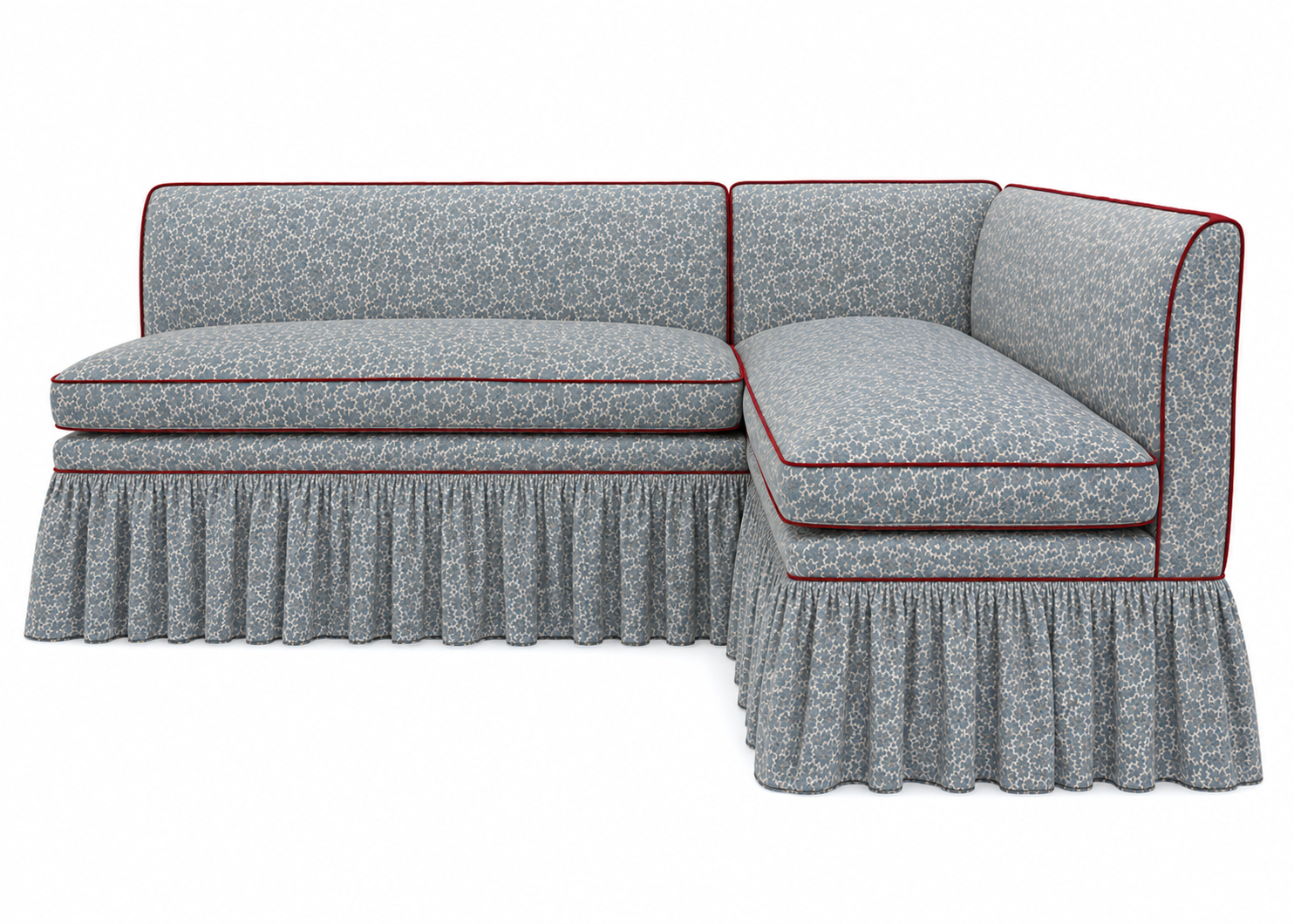 A blue and white patterned sectional sofa with red piping, featuring a skirted bottom.