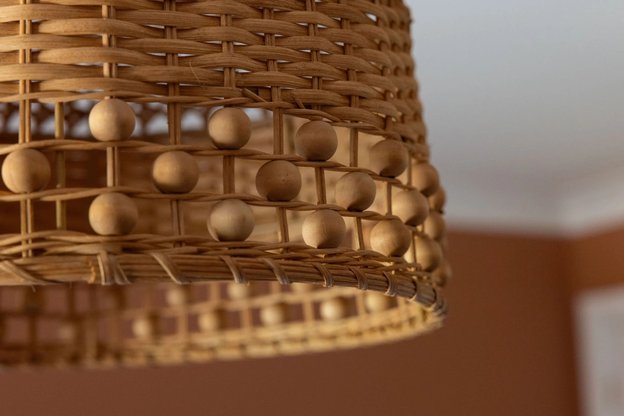 Close-up of a woven rattan lampshade with circular wooden accents, against a plain background.