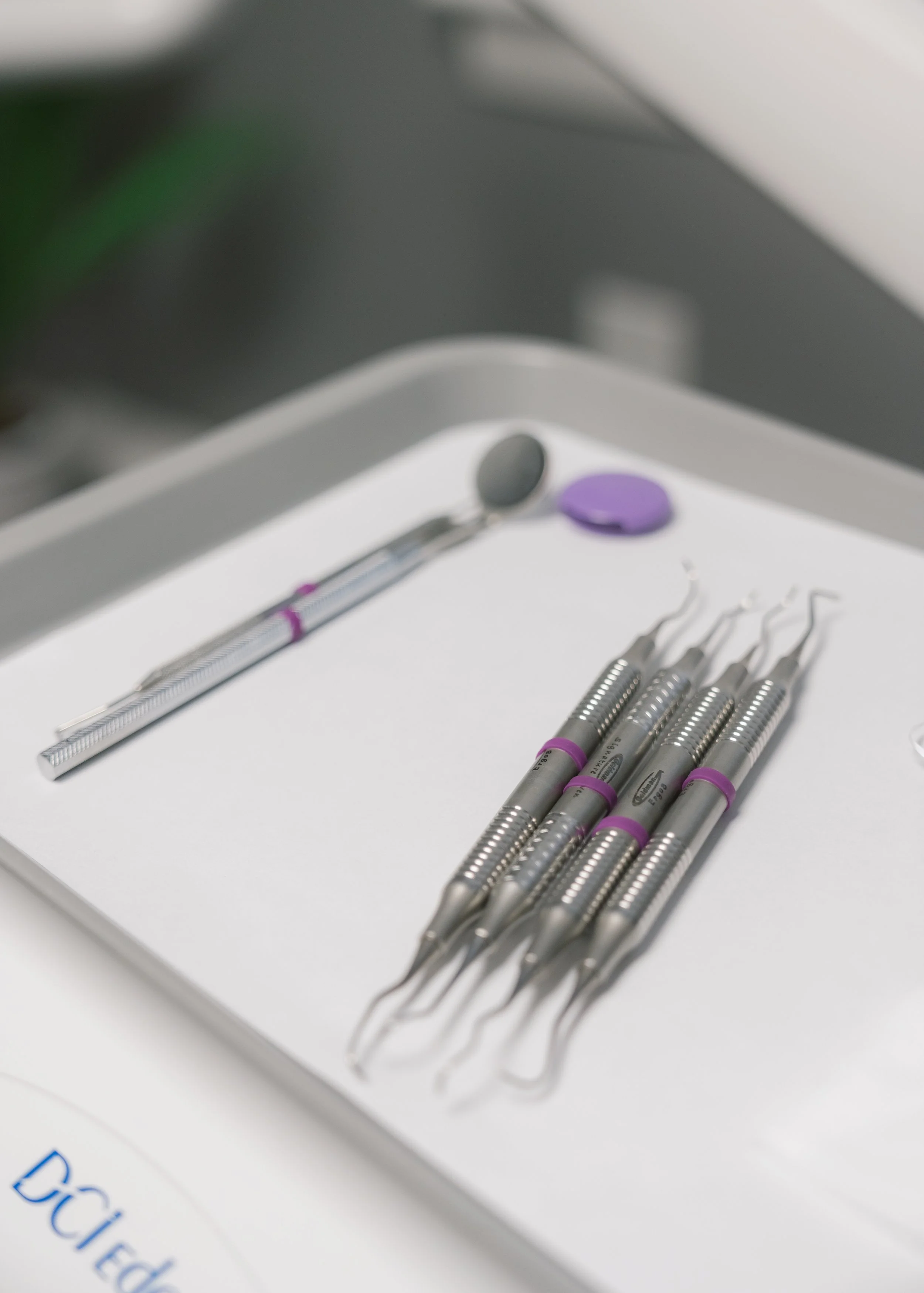 Close-up of dental tools, including a dental mirror and other instruments, arranged on a white tray.