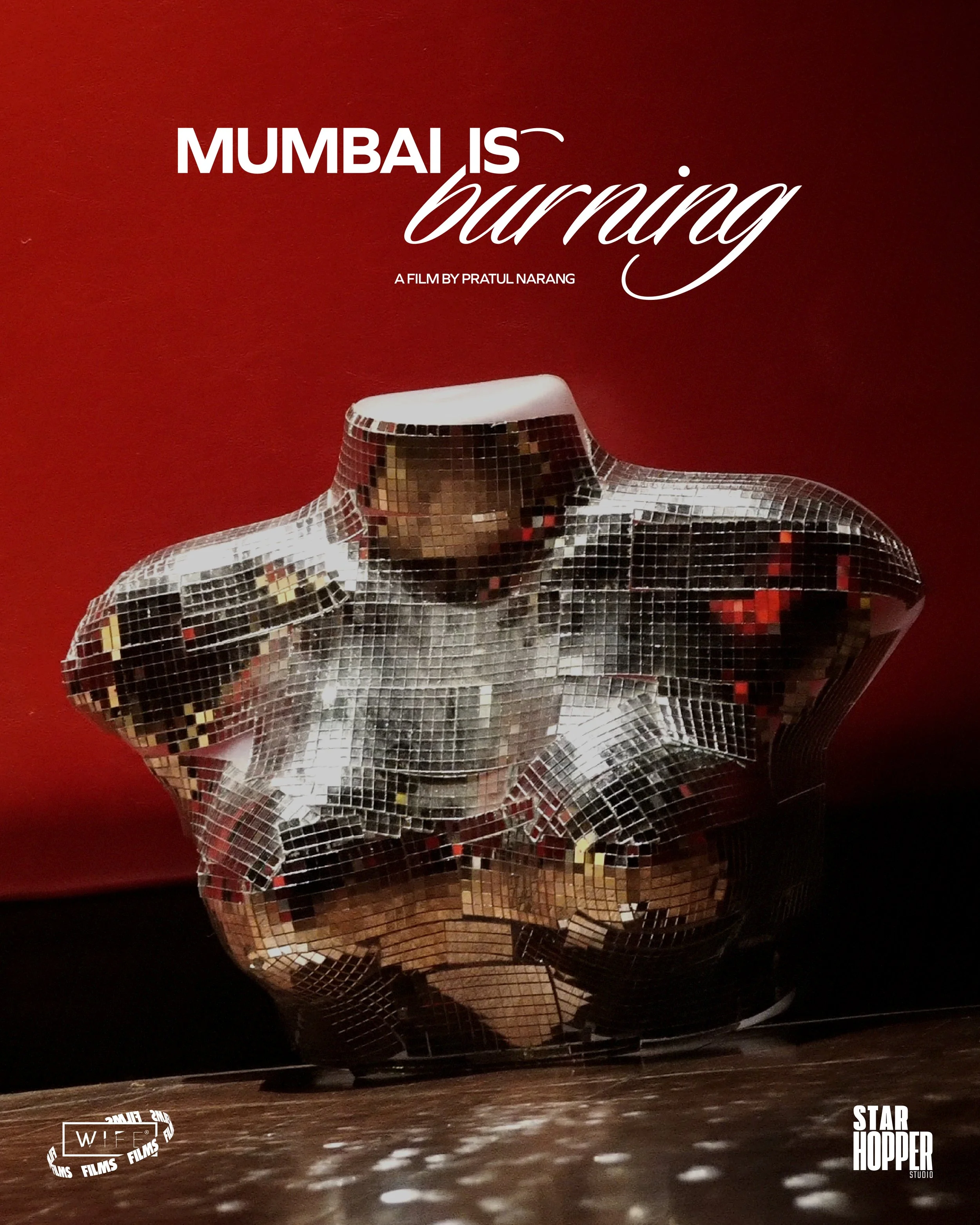 A reflective disco ball sculpture of a human figure on a dark stage with red background, with subtitles "MUMBAI IS burning" and logos "WIFE FILMS" and "STAR HOPPER STUDIO".