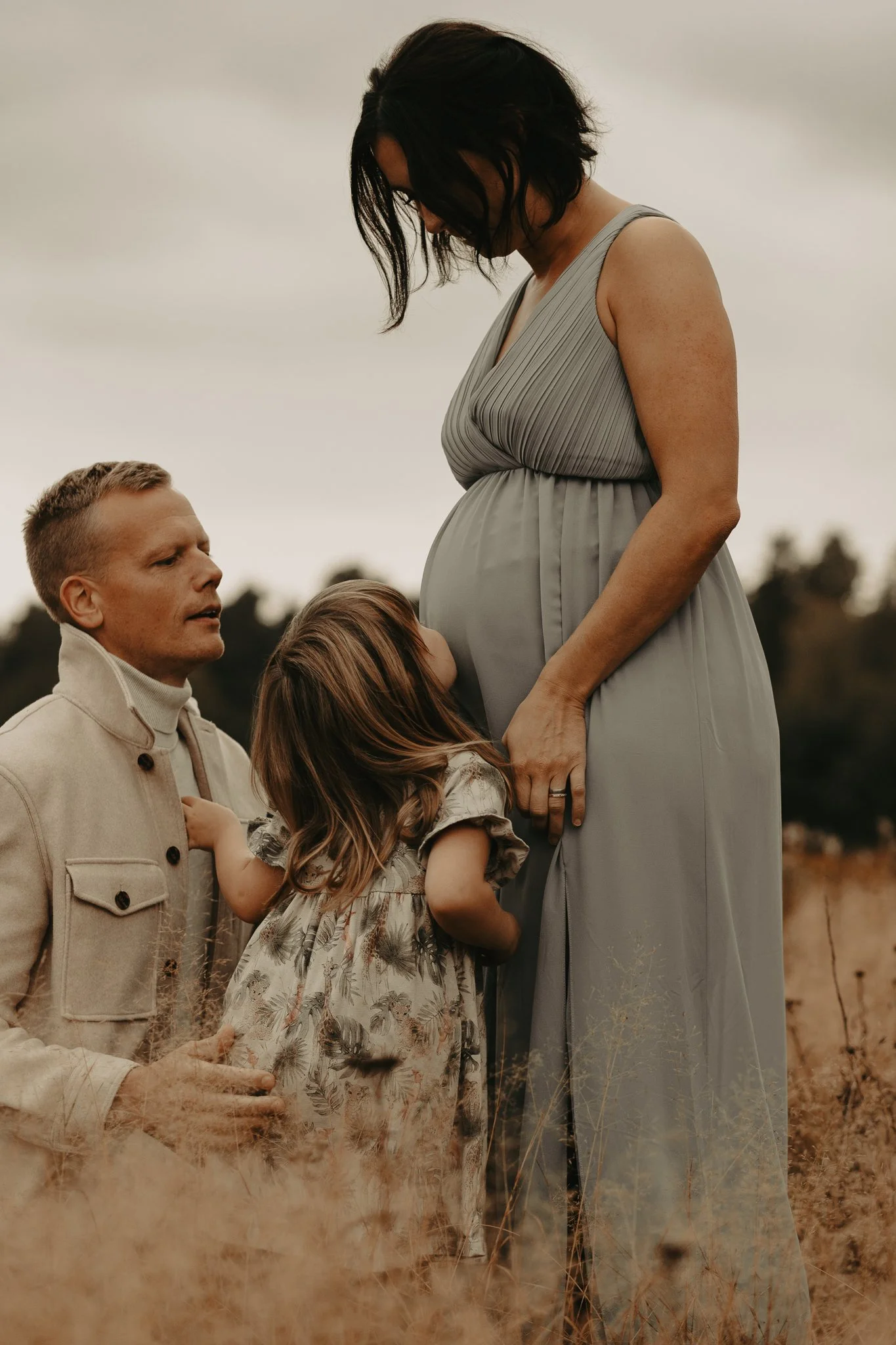 Gravid mamma får puss på magen av dotter
