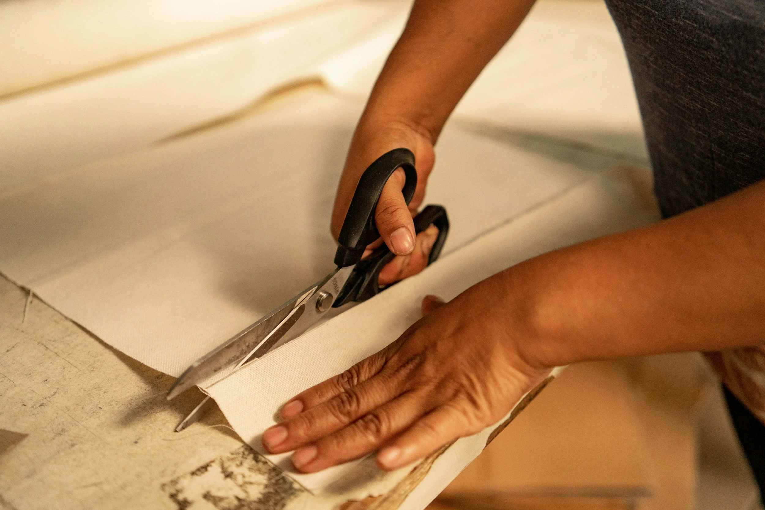 Person cutting a tile on the floor with a pair of large scissors.