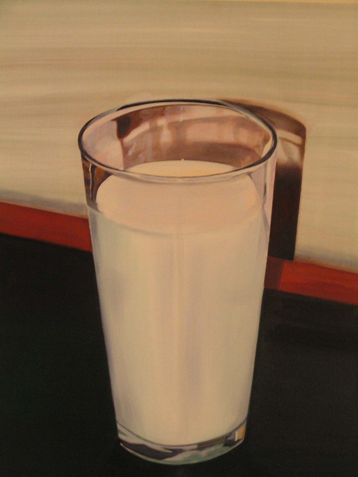 A glass of milk on a table with a wooden backdrop.