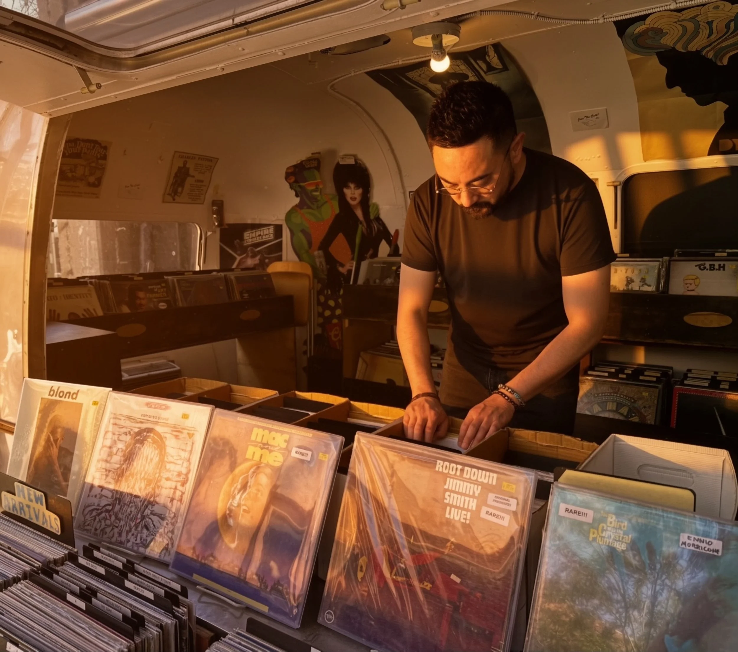 A man with glasses and a beard looking at records inside a record store.