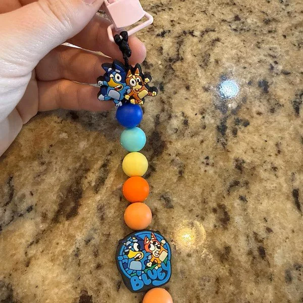 Colorful beaded keychain with cartoon characters and the name 'Bluey' on a granite countertop.