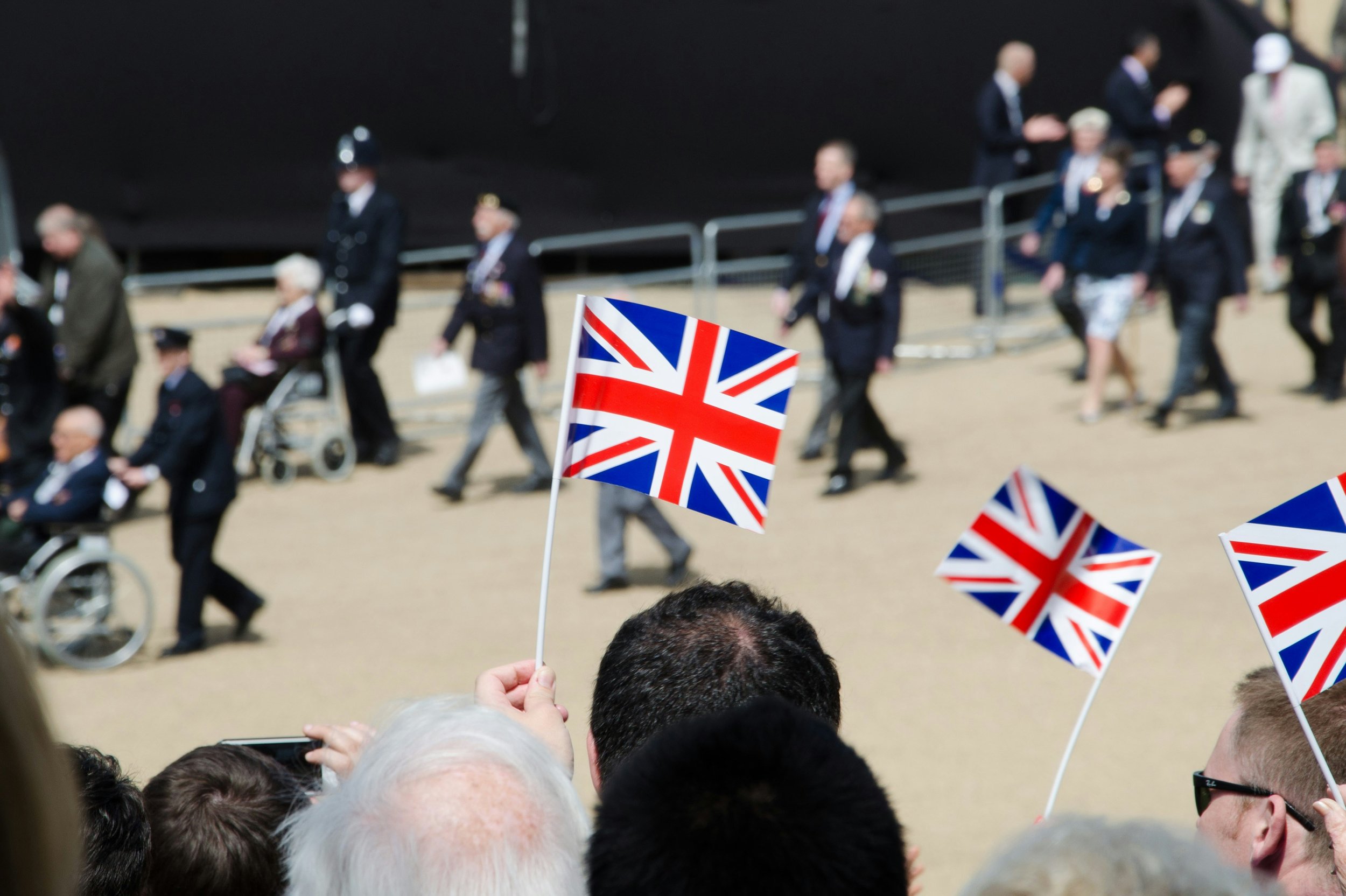 People gathered outdoors holding small flags with the design of the Union Jack.