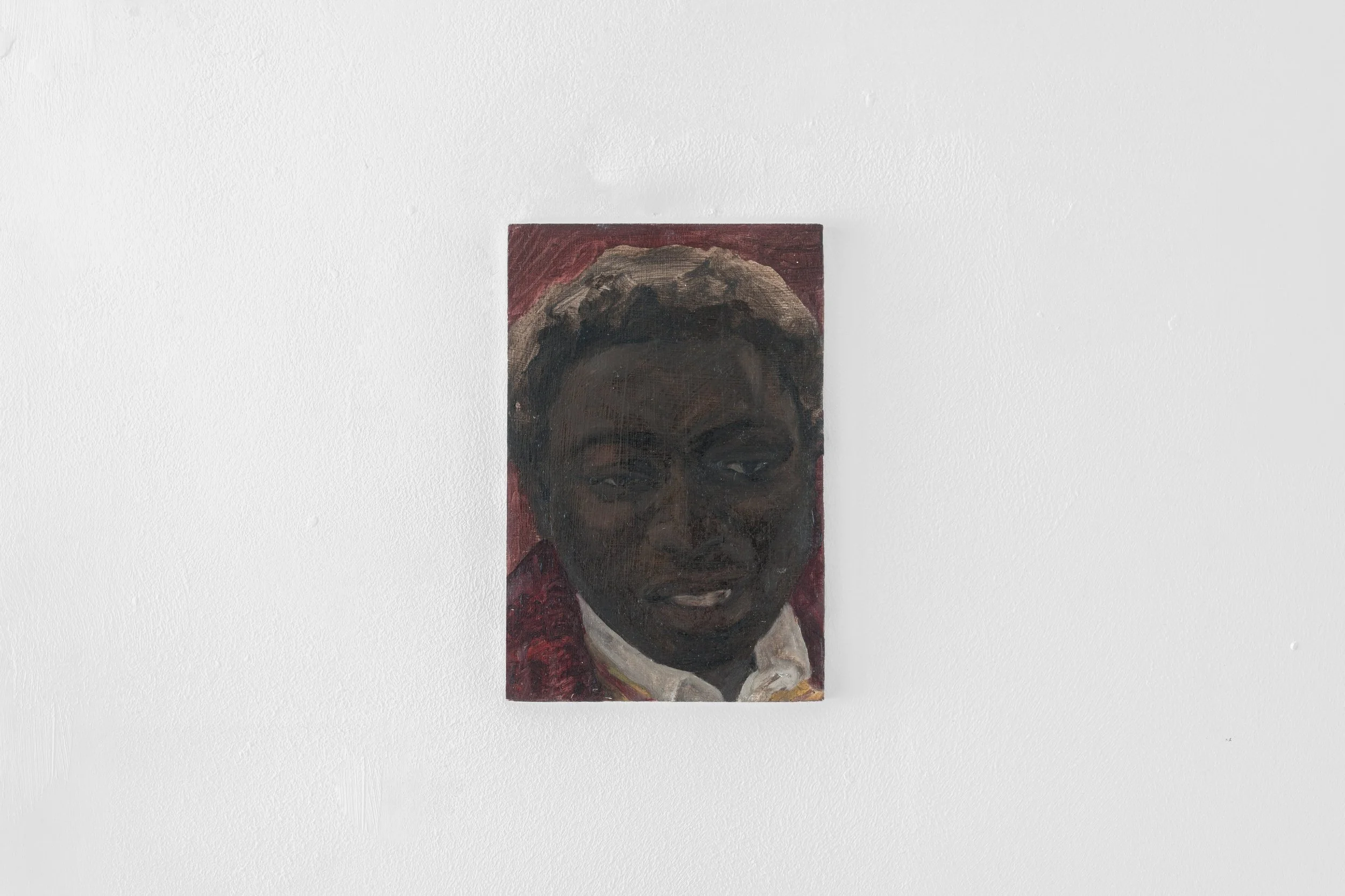 Painting of a black man's face on a white wall.
