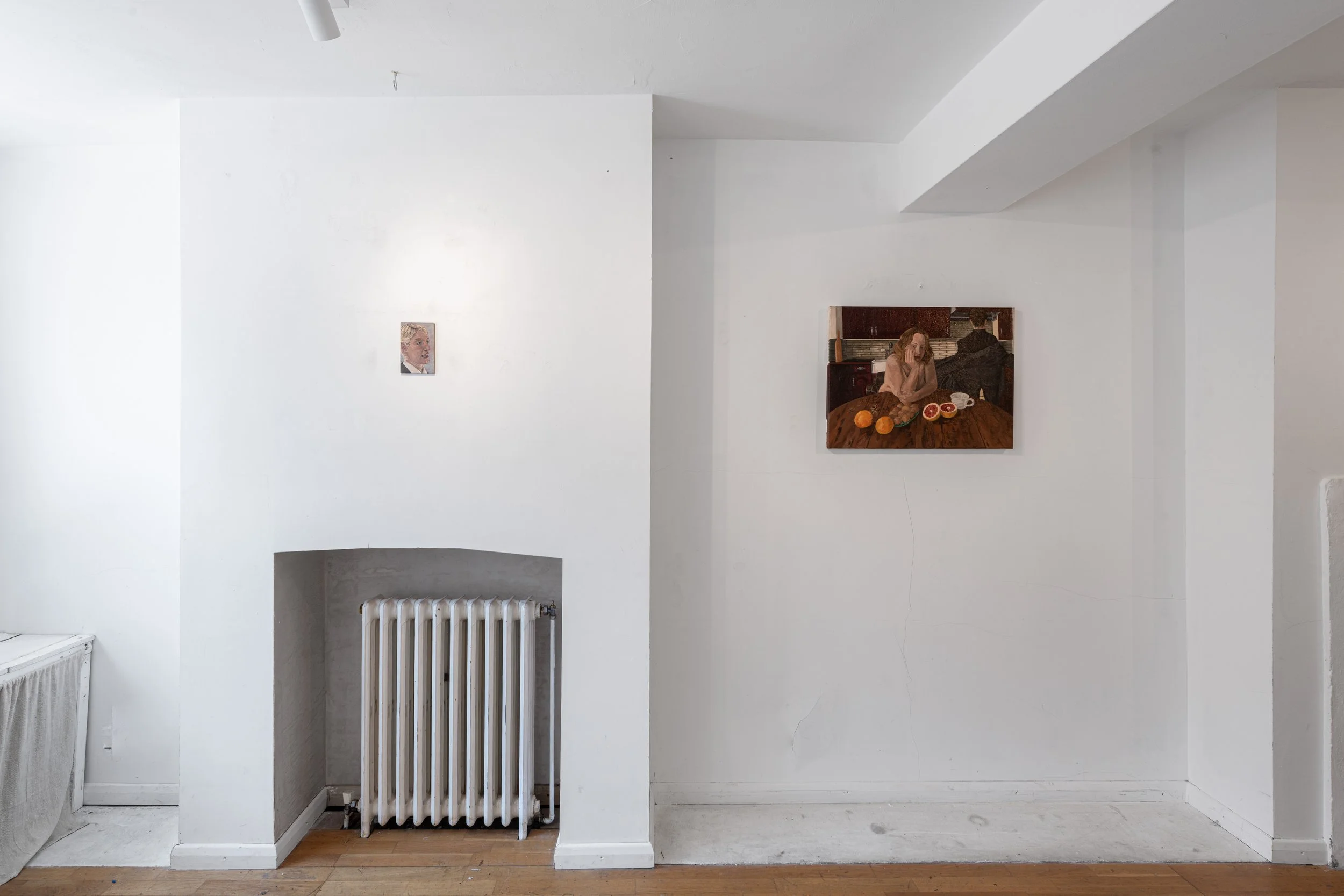 White interior wall with two paintings, radiator, radiator cover, and hardwood floor.