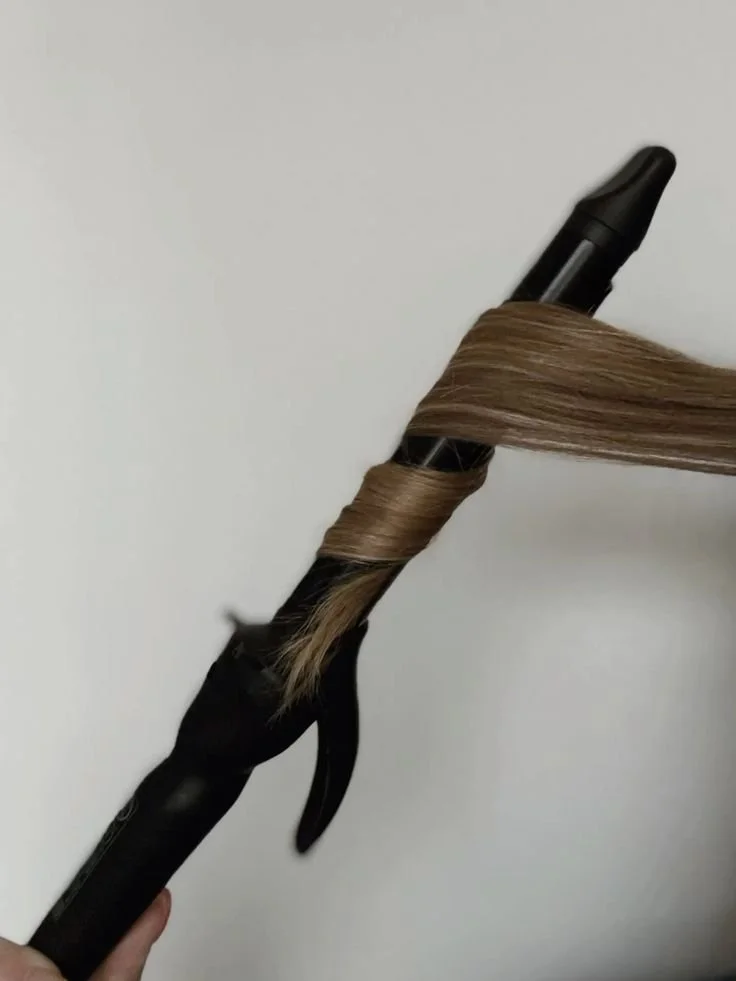 A curling iron wrapping a section of blonde hair