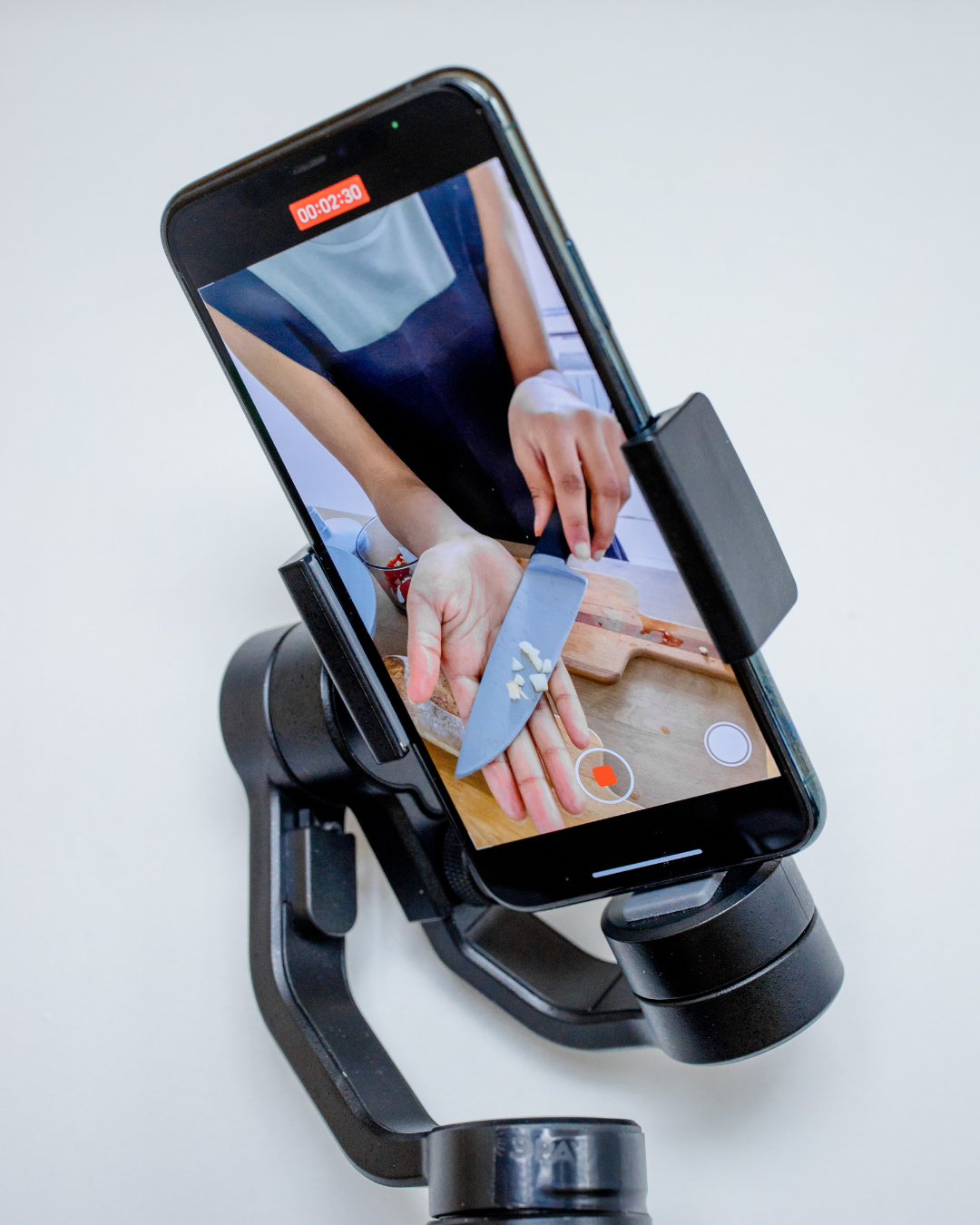 Smartphone on a gimbal recording a person chopping garlic on a cutting board