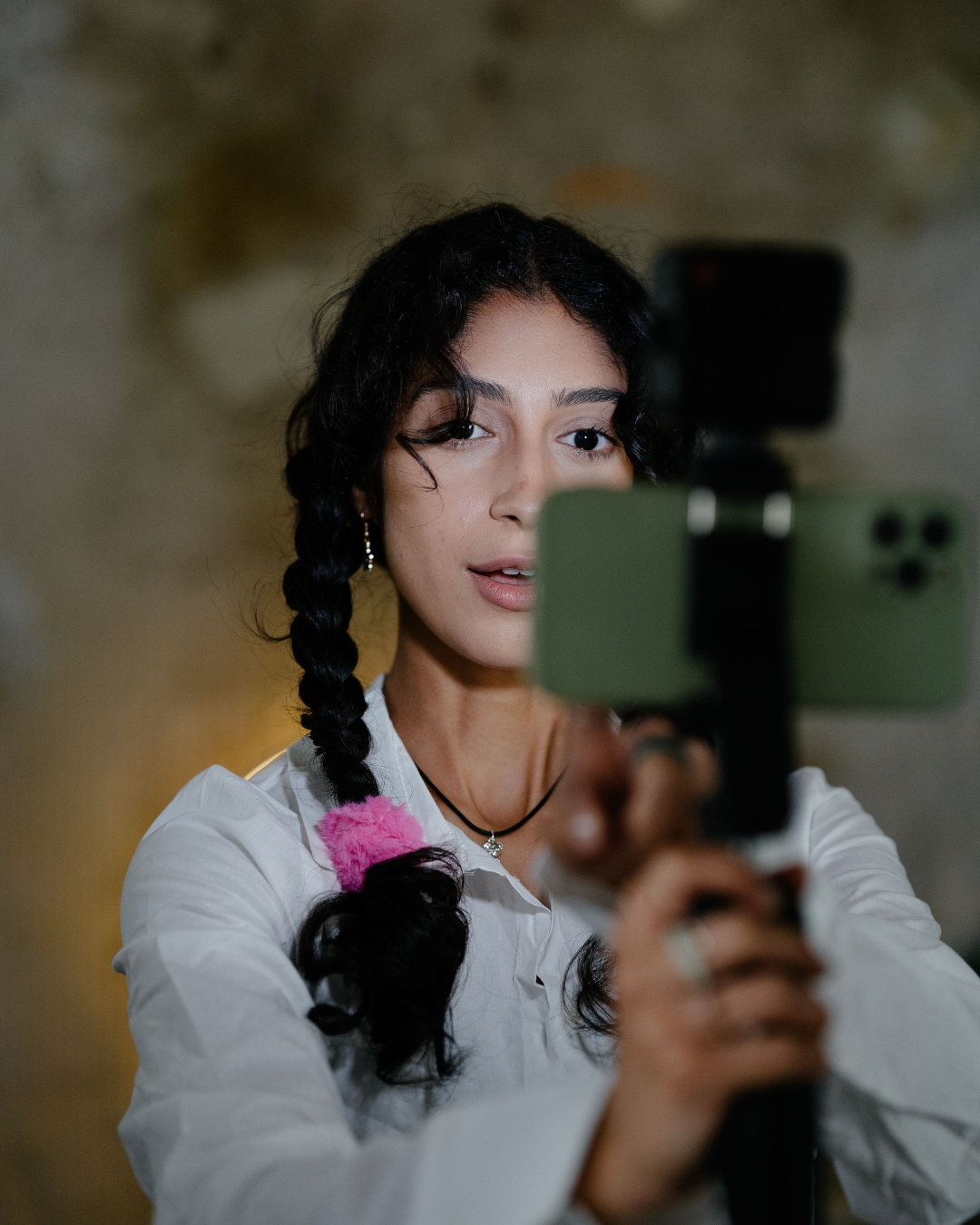 Woman with braided hair taking a mirror selfie with a smartphone