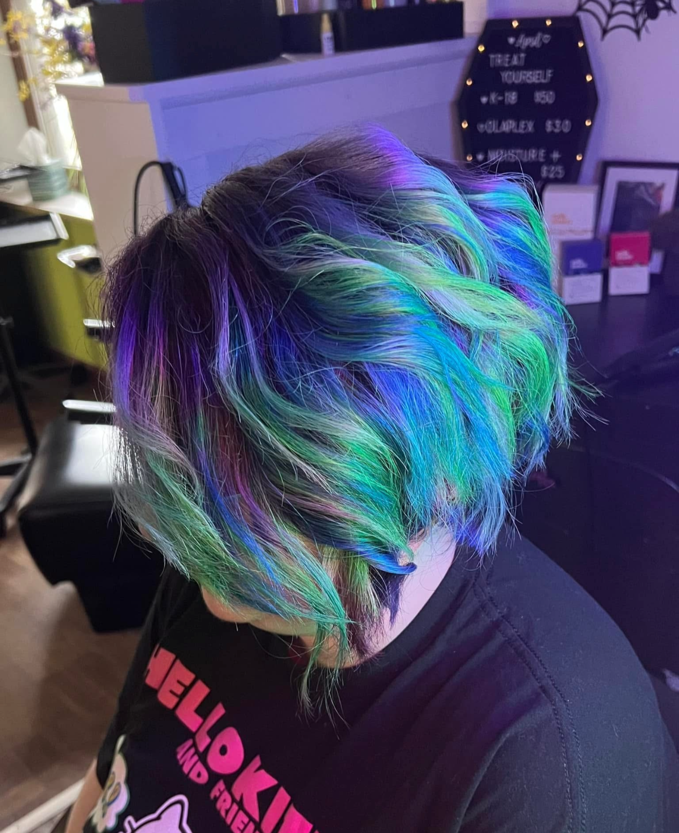Person with short, multi-colored rainbow hair dyed in shades of purple, blue, green, and pink.