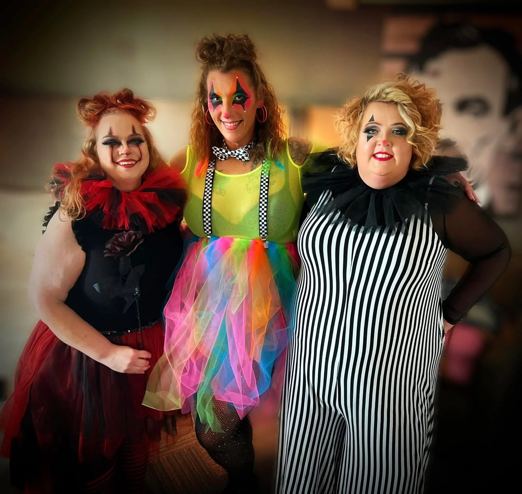 Three women dressed as clowns smiling together at a costume party.
