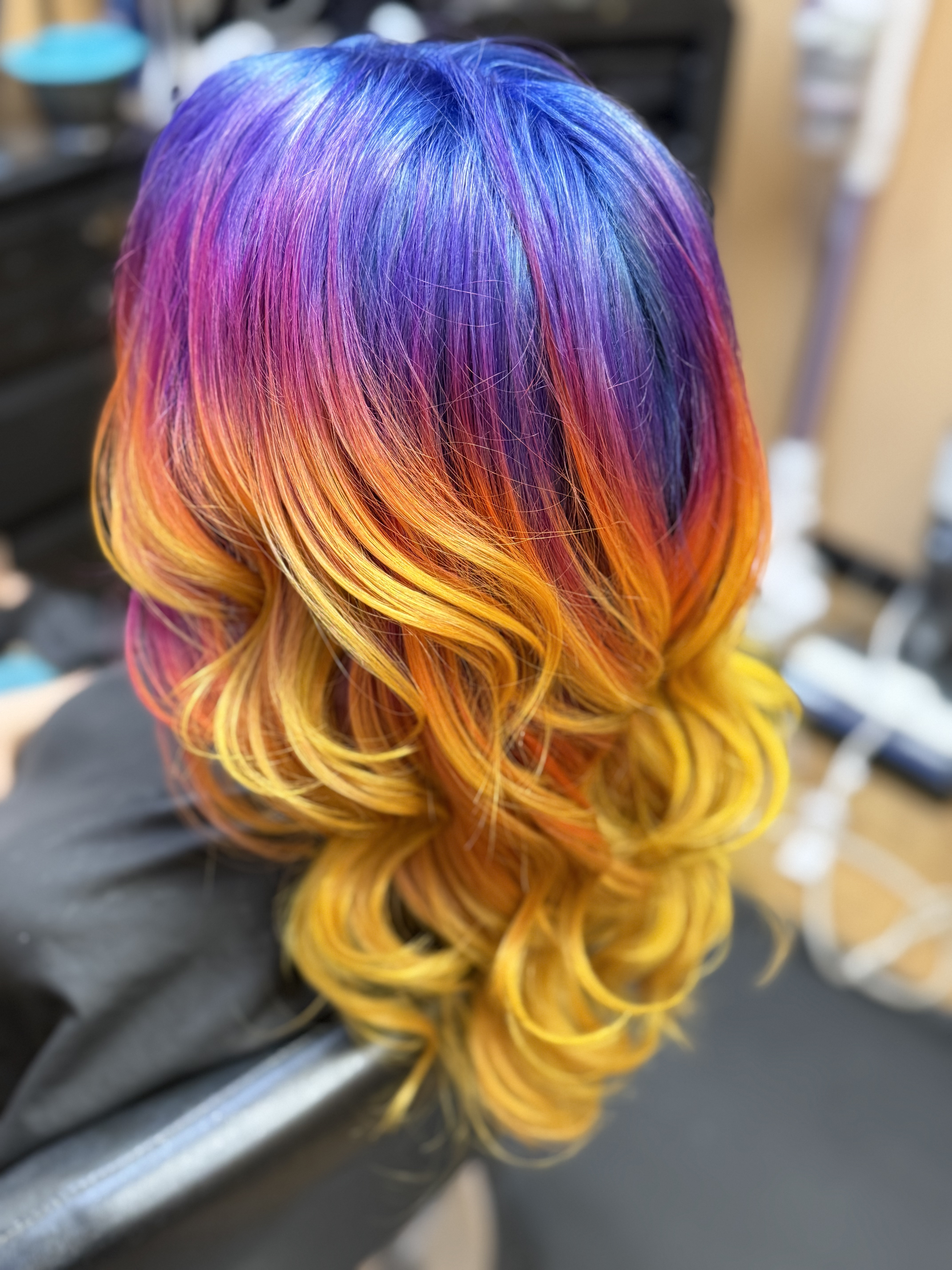 Close-up of colorful, curled hair with shades of purple, pink, orange, and yellow.