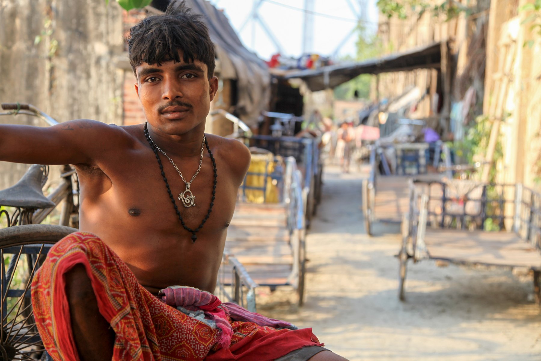 A man sits in a narrow lane of a neighbourhood along the Hooghly River in Kolkata, West Bengal, India. The portrait documents everyday life in one of the communities lining the city’s historic waterfront.